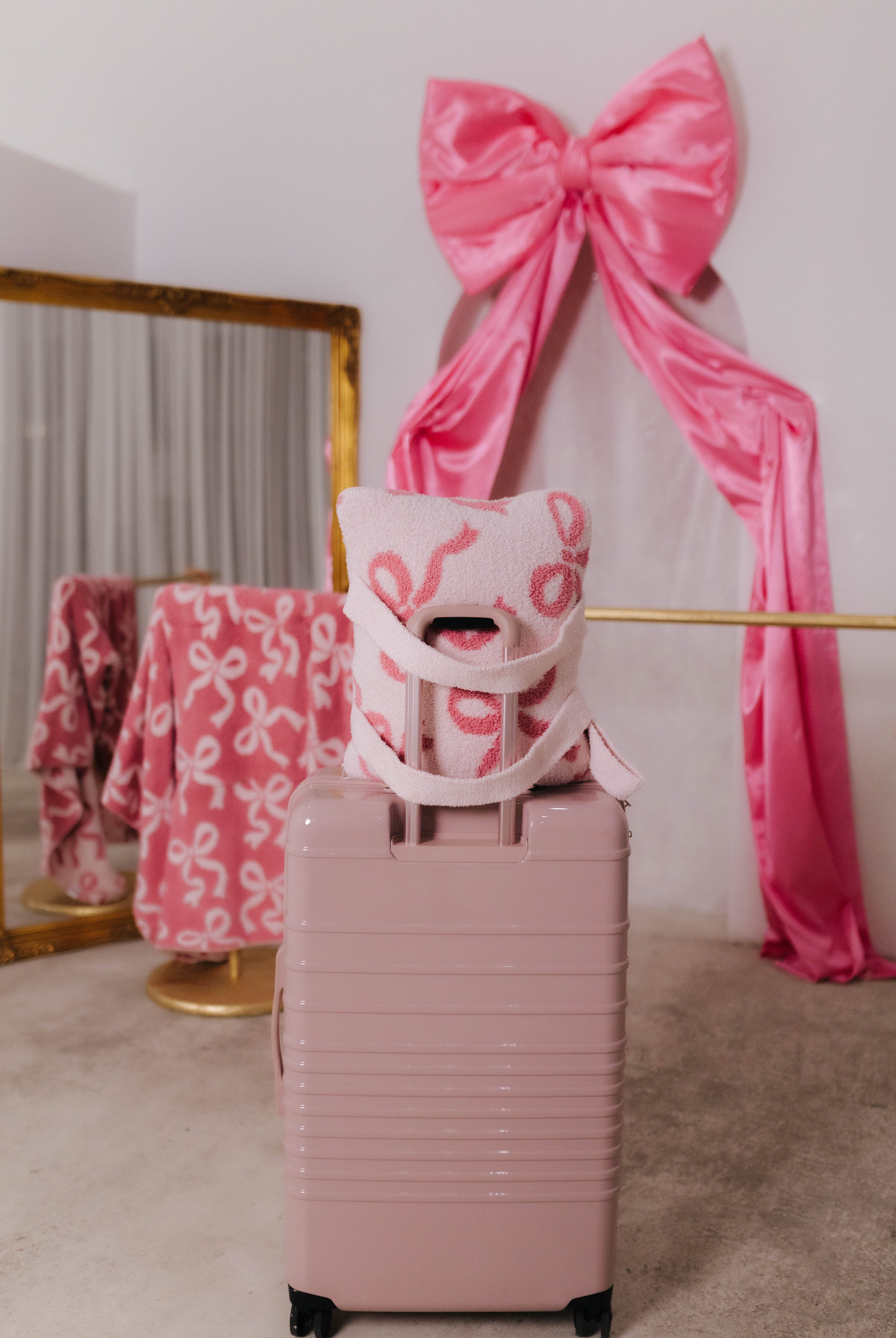 Pink suitcase with a pink bow and decorative quillow in a room setting