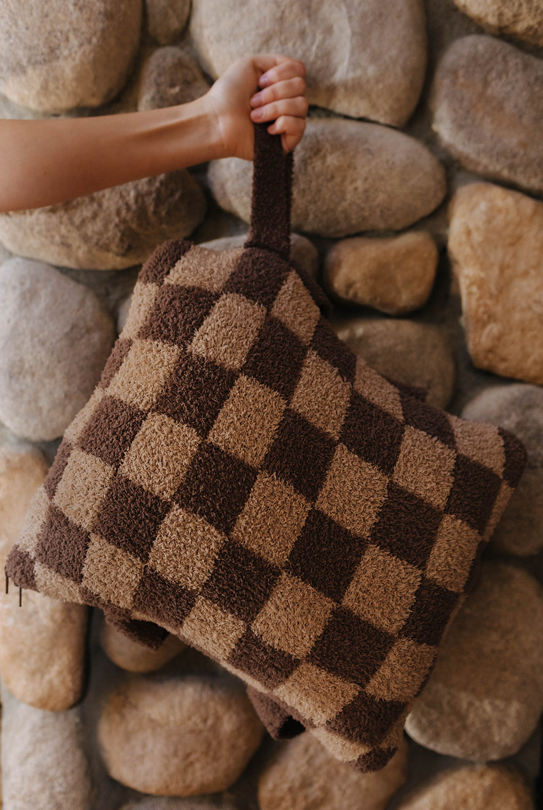 Brown check quillow folded into a pillow with a wrist strap.