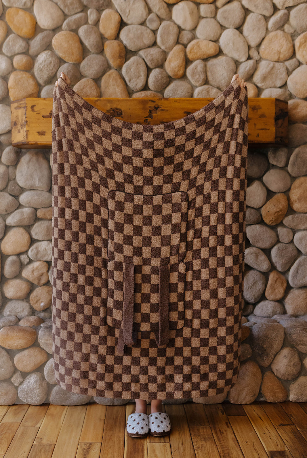 Tonal brown check quillow opened into a blanket with the pocket and straps visible.