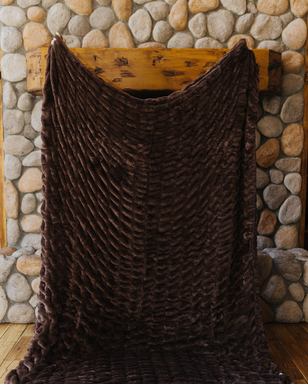 Brown faux fur blanket held open to show its plush ridged texture.