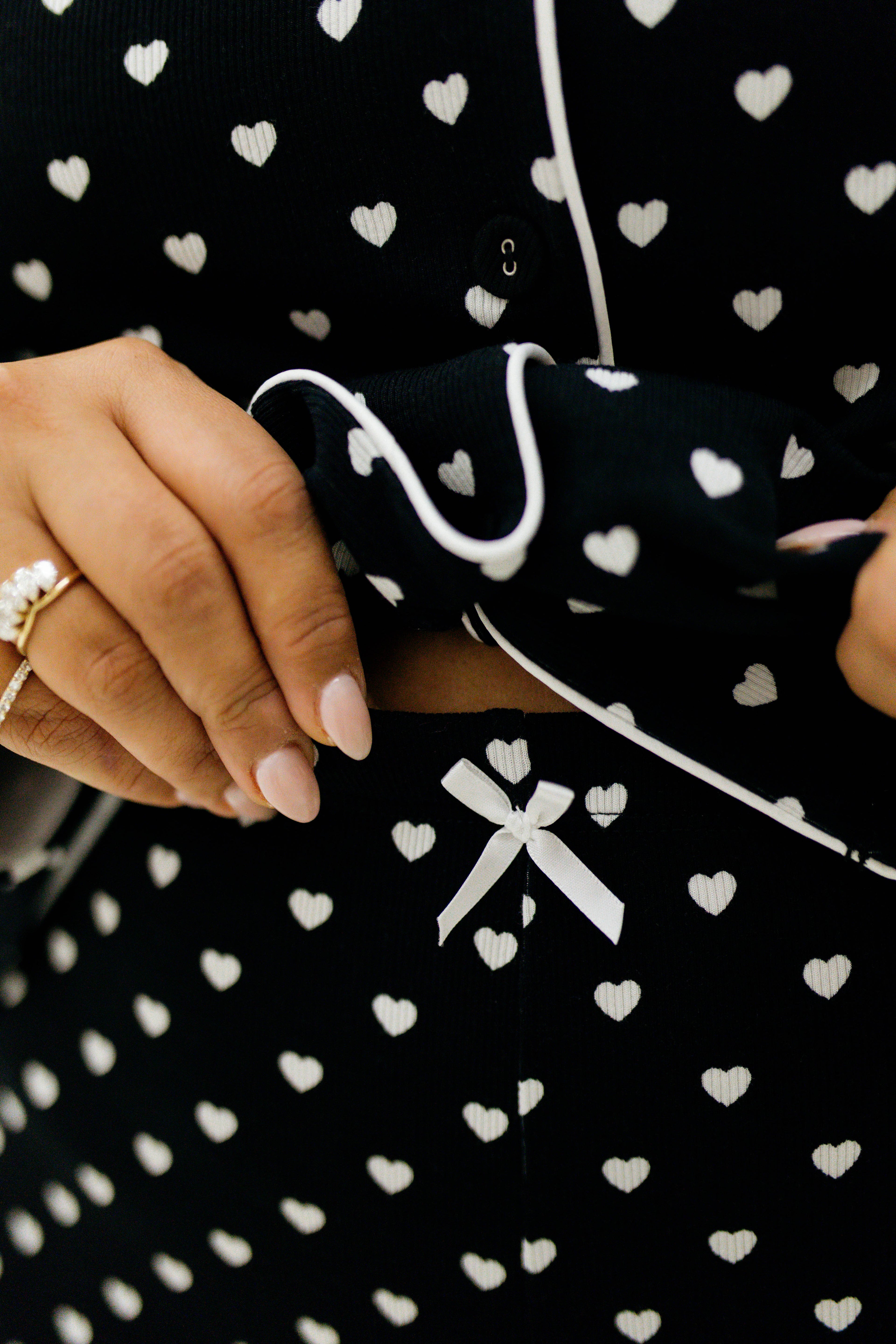 Black fabric with white heart patterns and a white ribbon design.