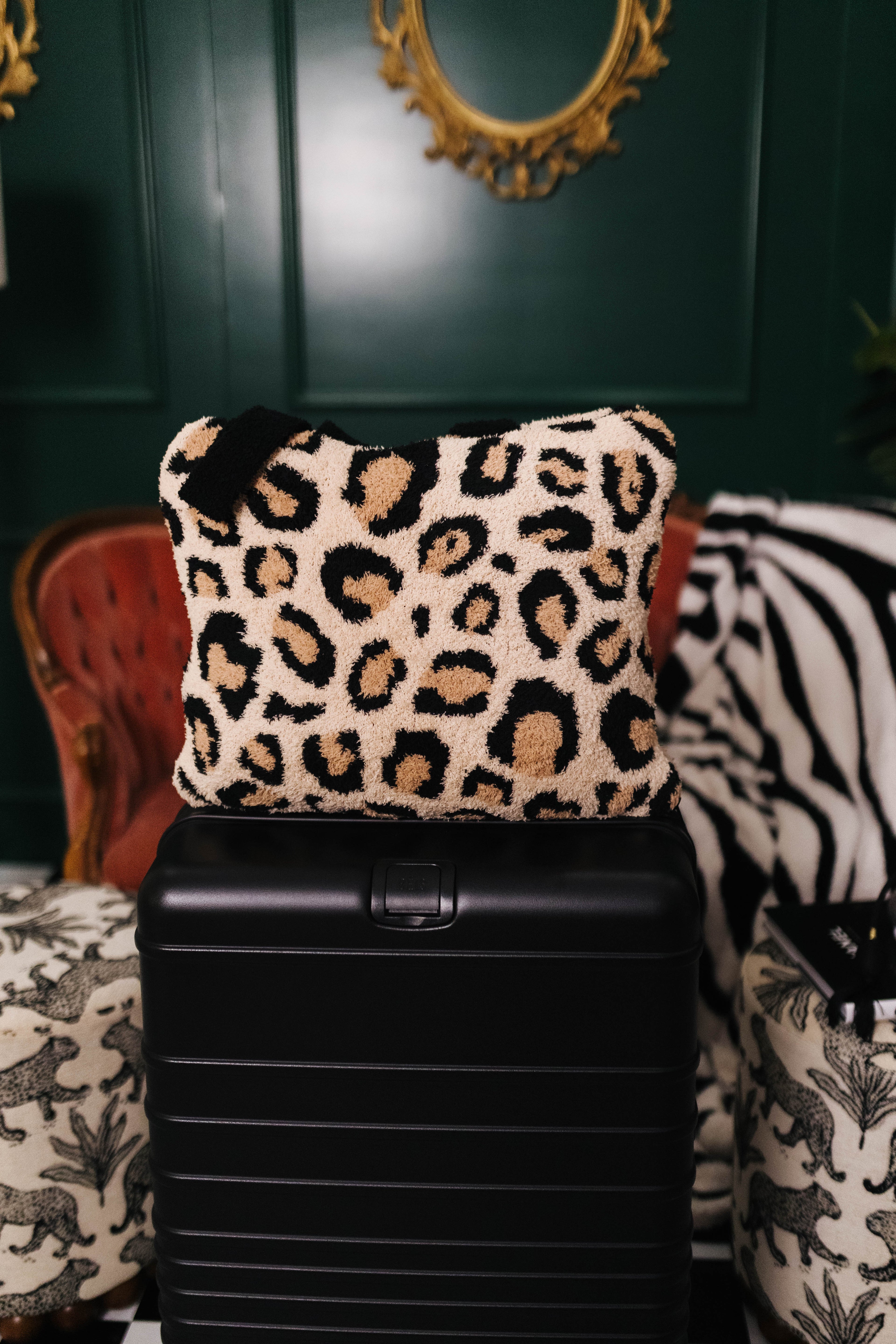 Leopard print quillow on a black suitcase with a decorative background