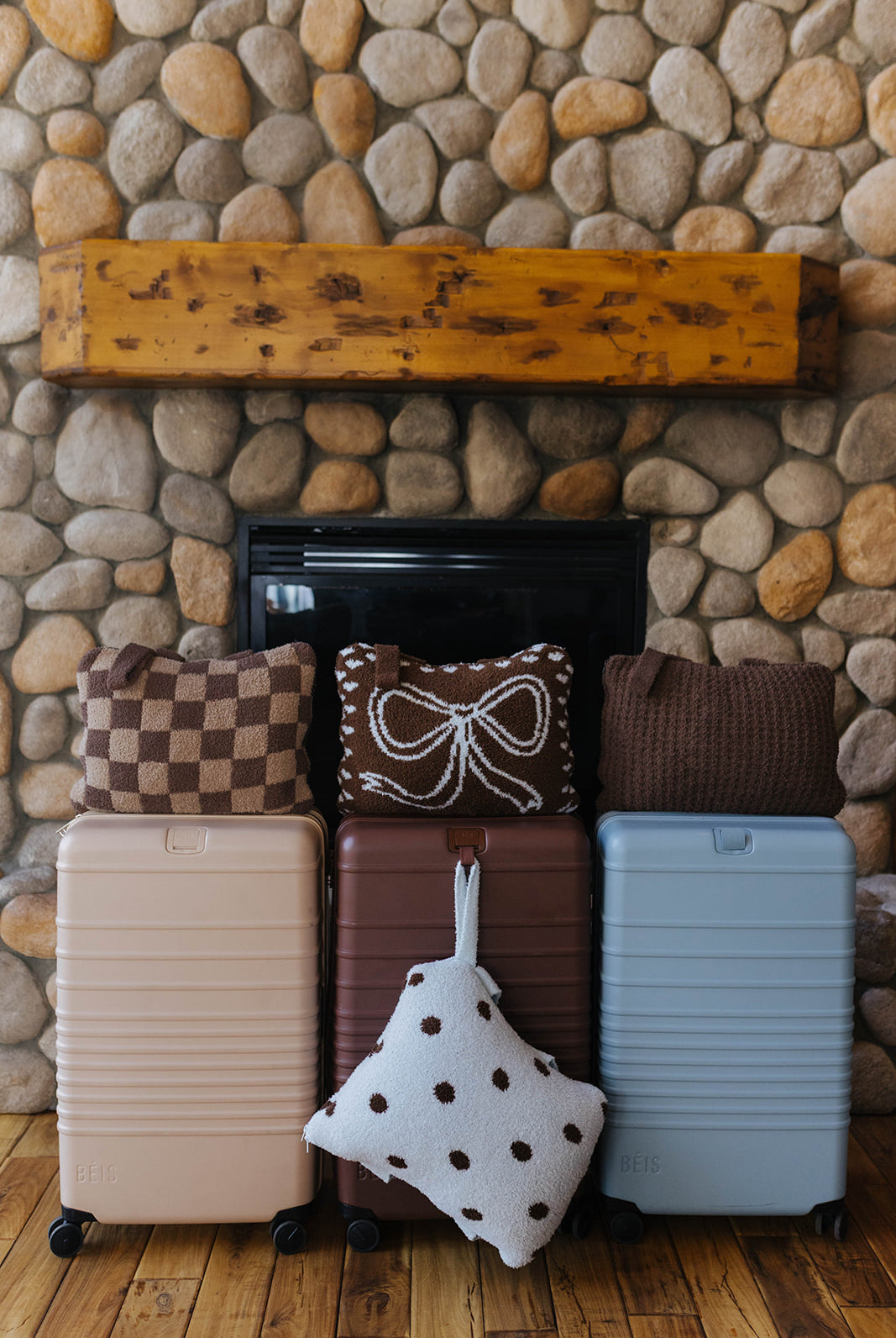 Check, bow, waffle, and polka dot quillows displayed with suitcases.