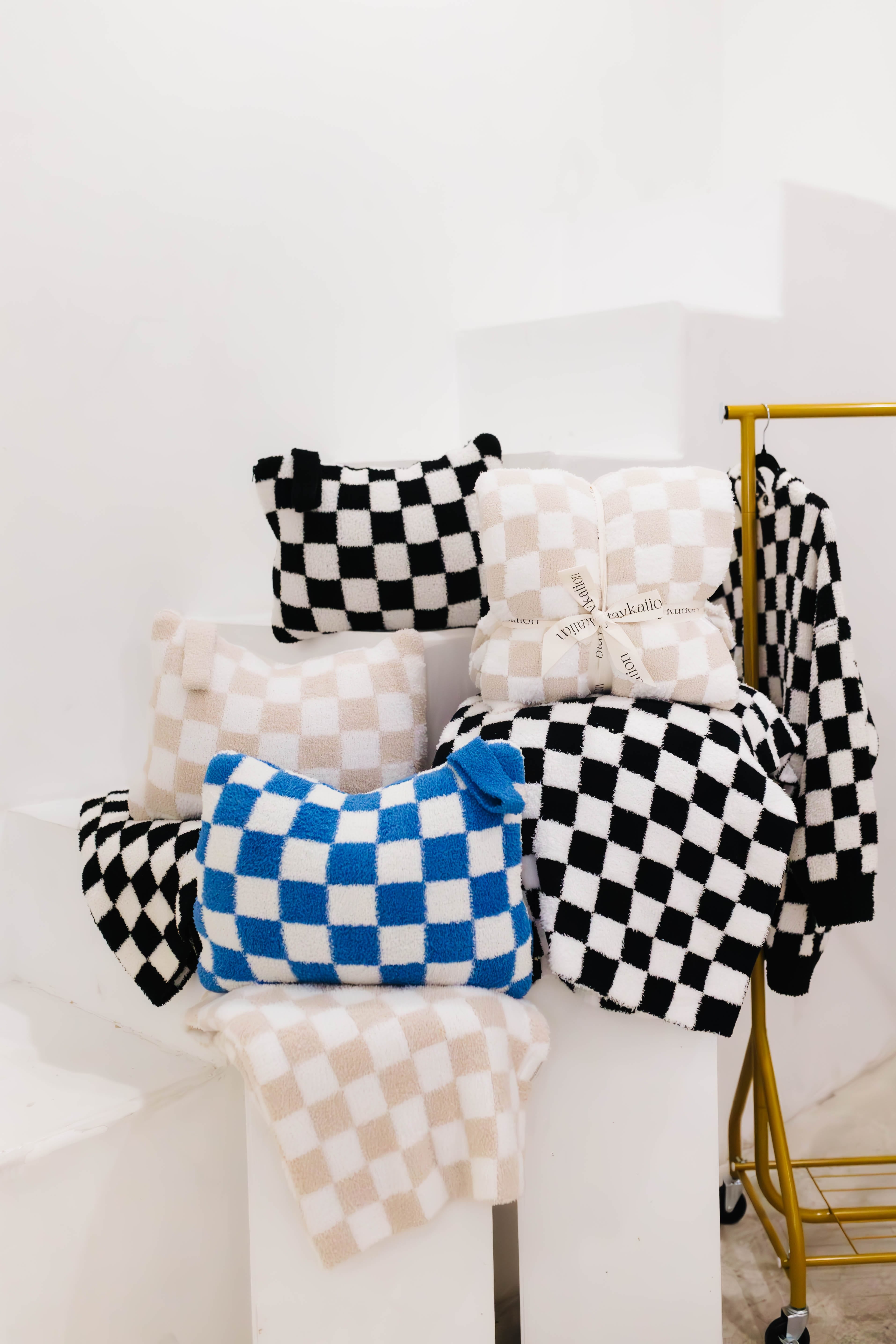 Checkered quillows and blankets in various colors on a white background