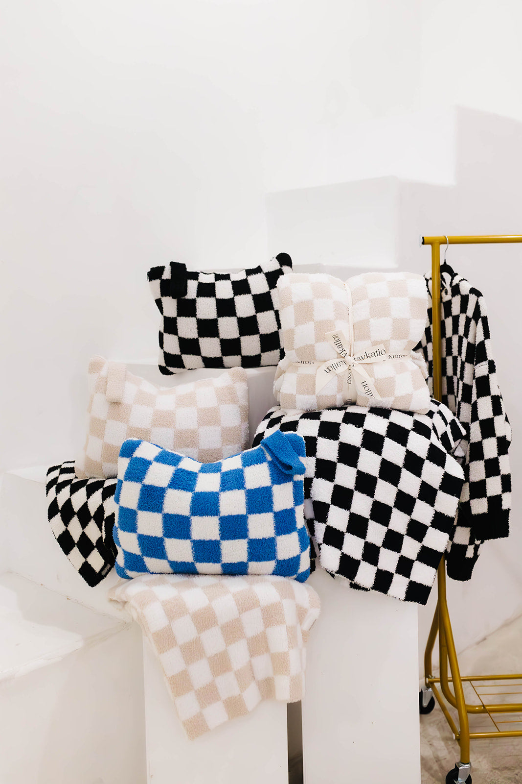 Checkered pillows and blankets in various patterns on a white surface with a blurred background