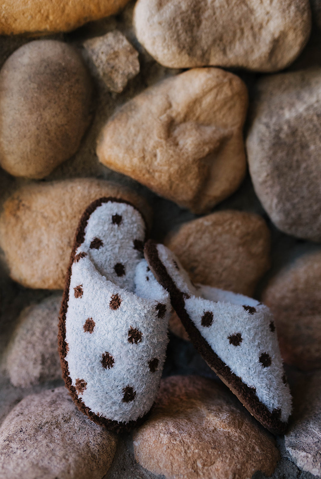 Blue slippers with brown polka dots displayed on a wood stool.