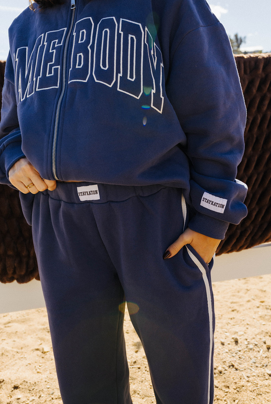 Close view of navy Homebody pants with white side piping, paired with the matching zip sweatshirt.