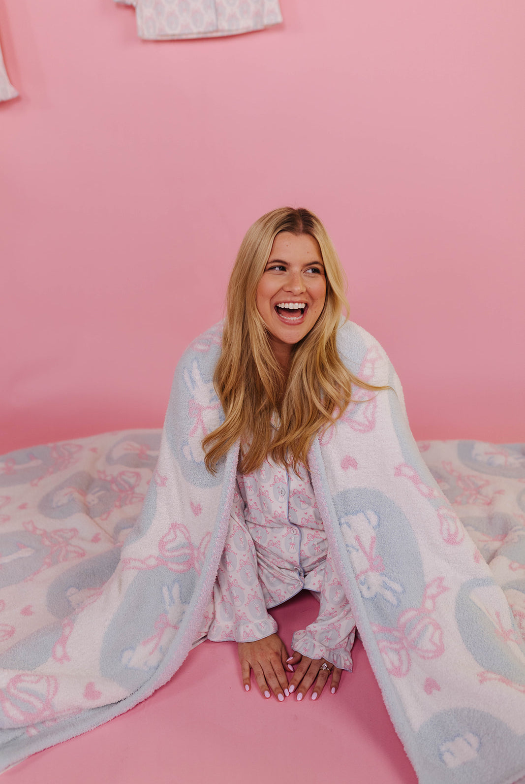 Woman wrapped in a patterned blanket on a pink ground