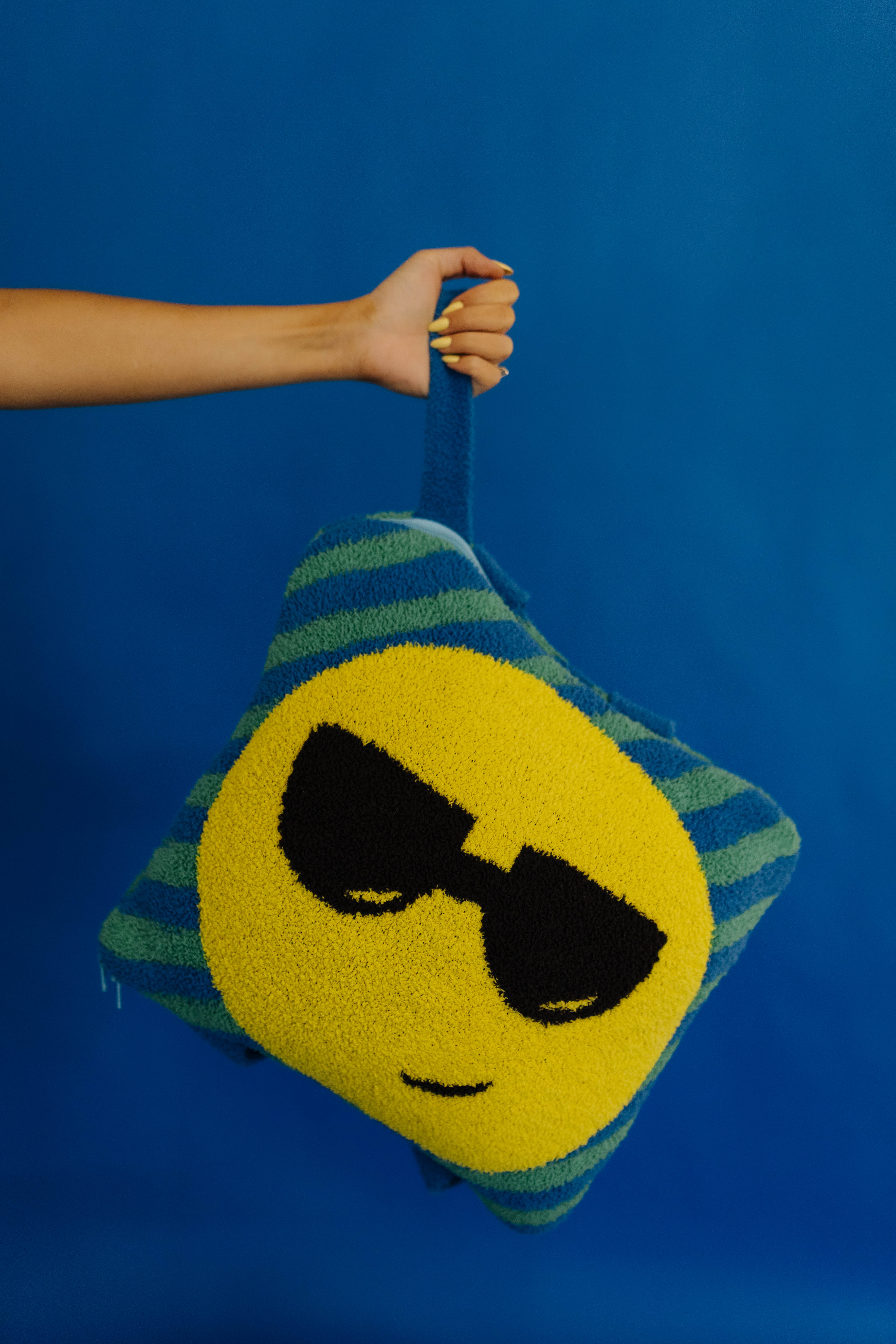 holding the quillow by the wristlet strap against a solid blue background