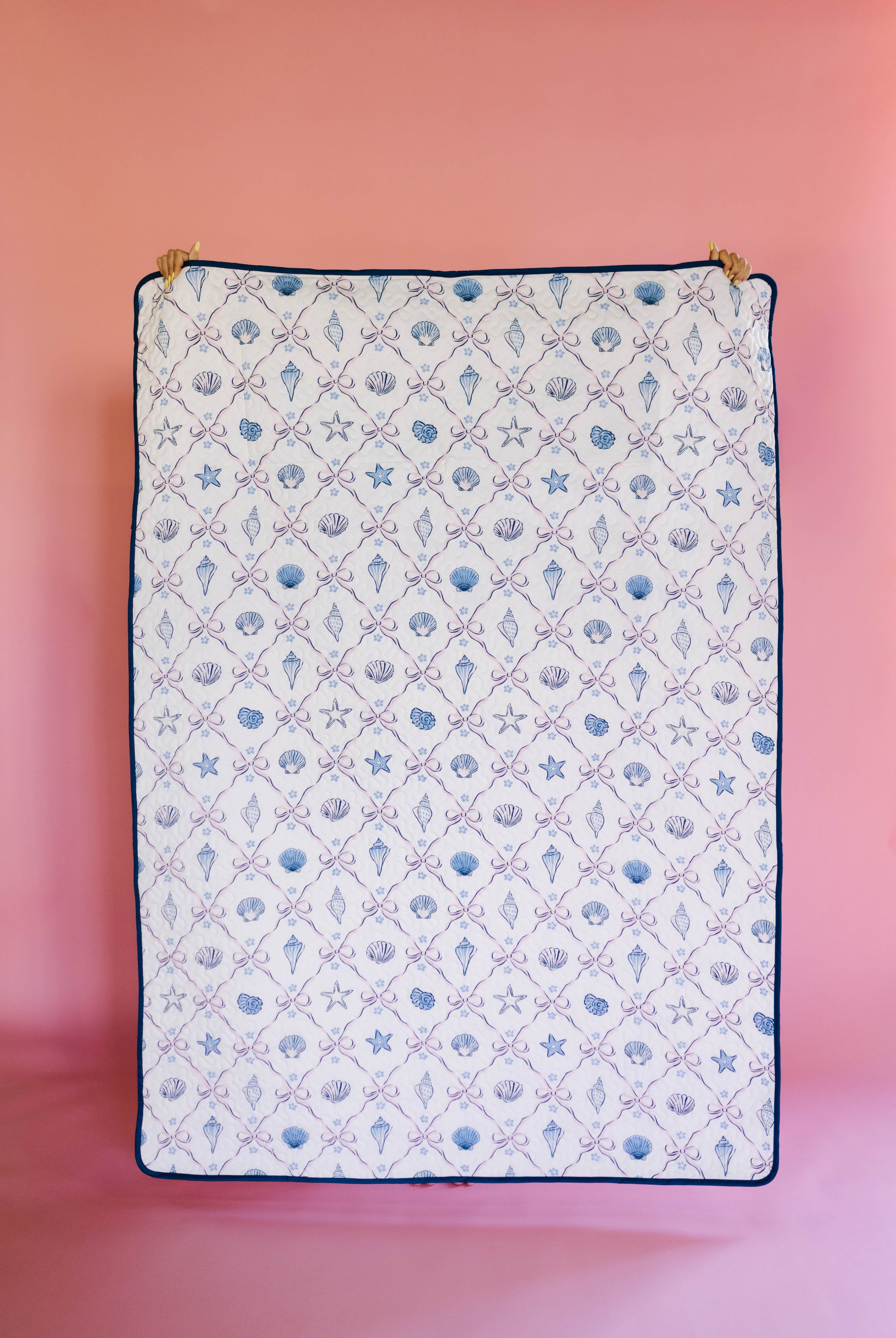 Patterned outdoor quillow/blanket with sea-themed design on a pink background