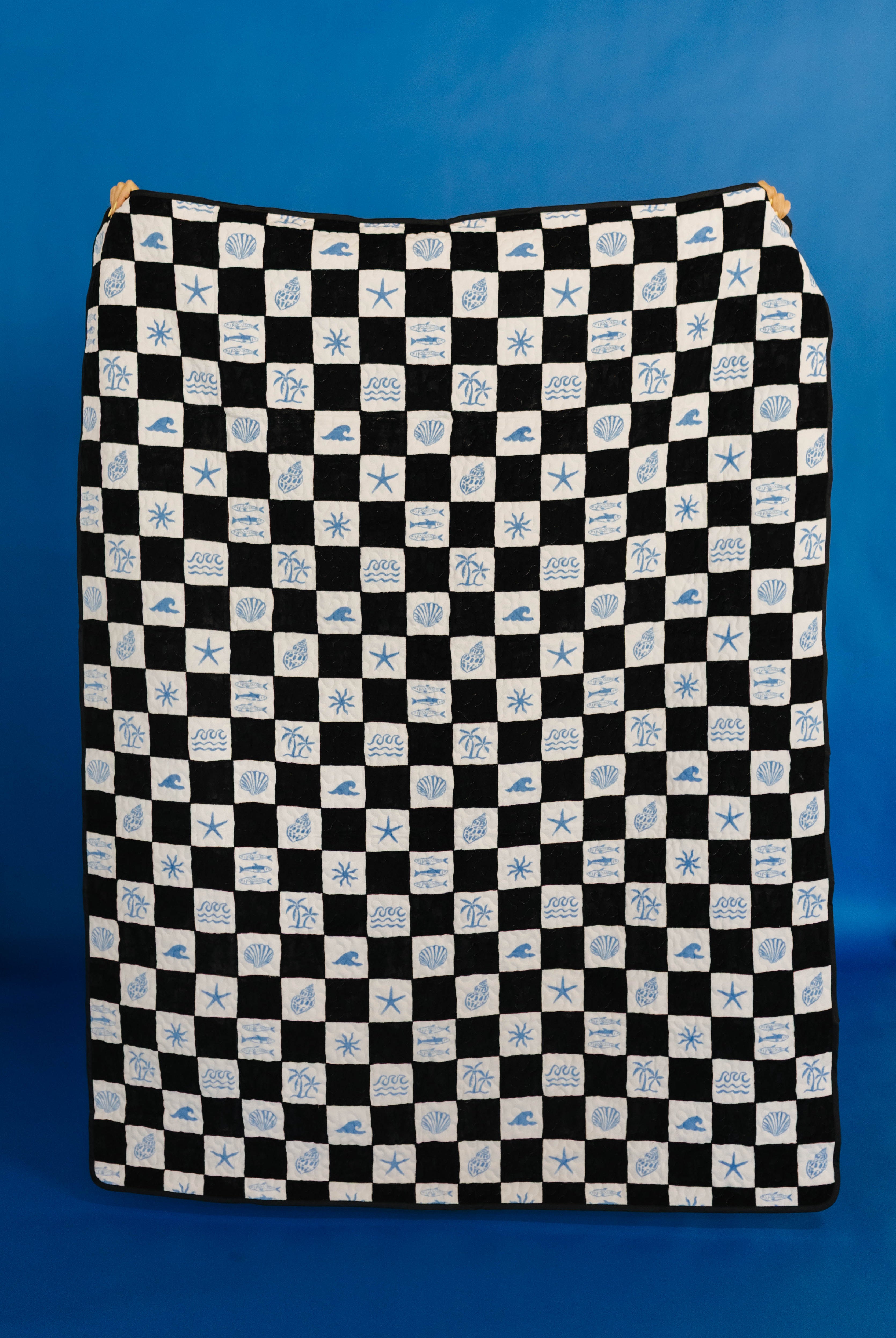 Black and white checkered picnic blanket with blue sea-themed pattern on a blue background