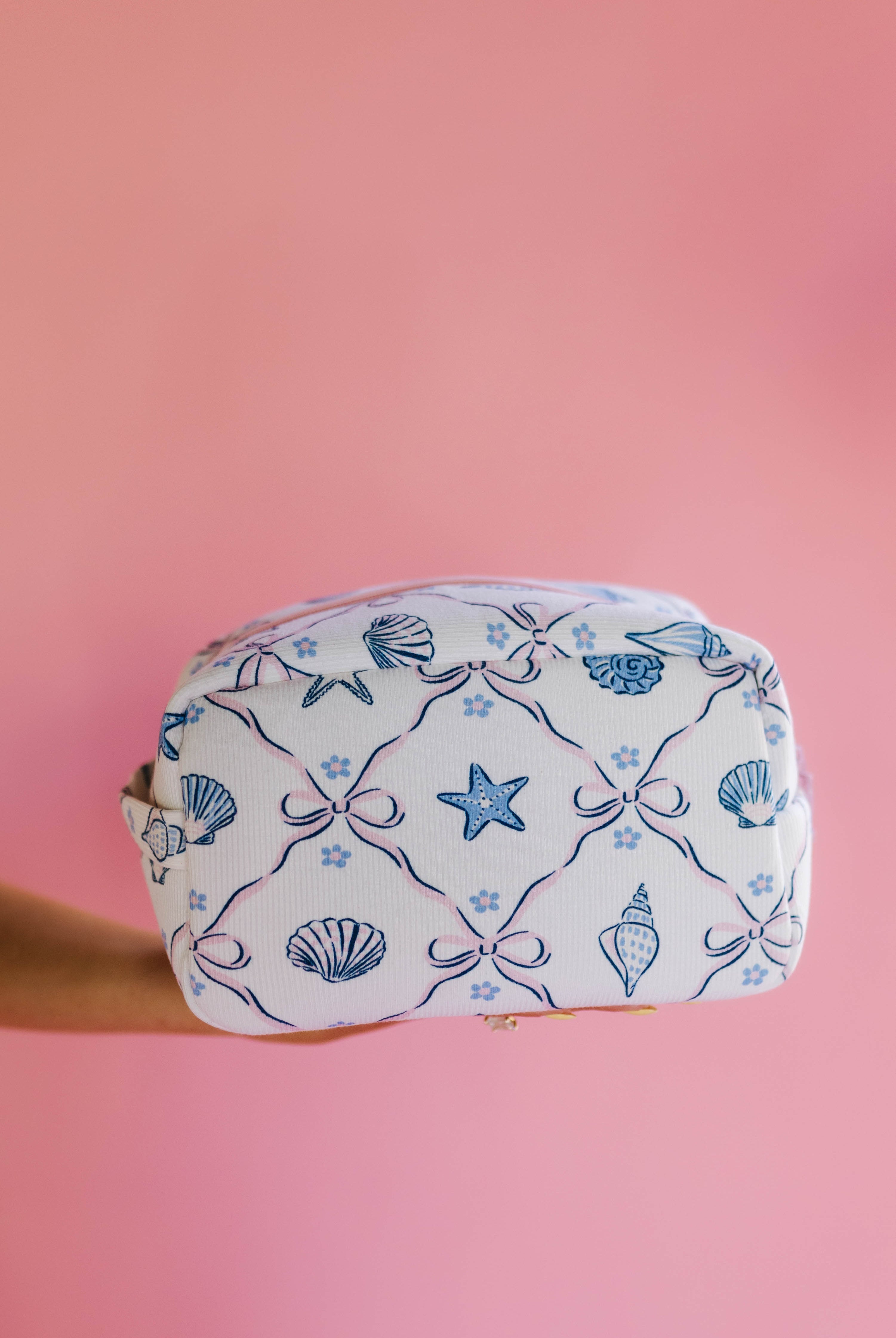 Cosmetic bag with shell and star pattern on a pink background