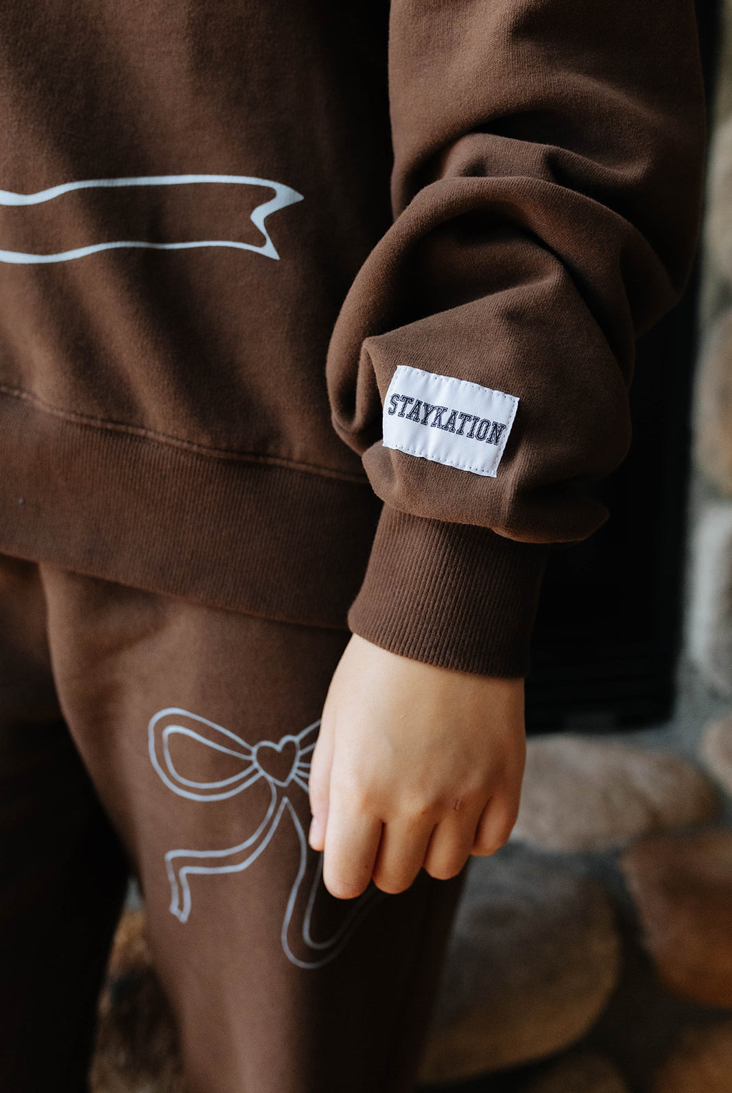 Close view of the brown bow sweatshirt cuff and bow graphic on the sweatpants.