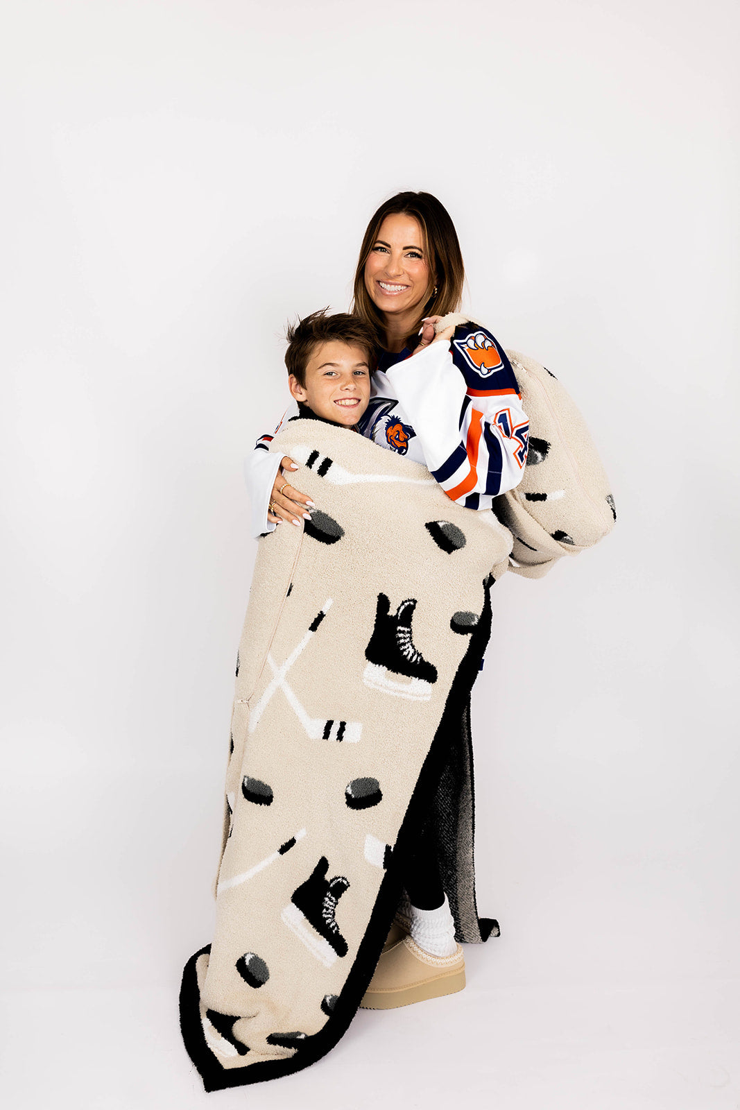 Two people wrapped in a blanket with hockey-themed design on a white background