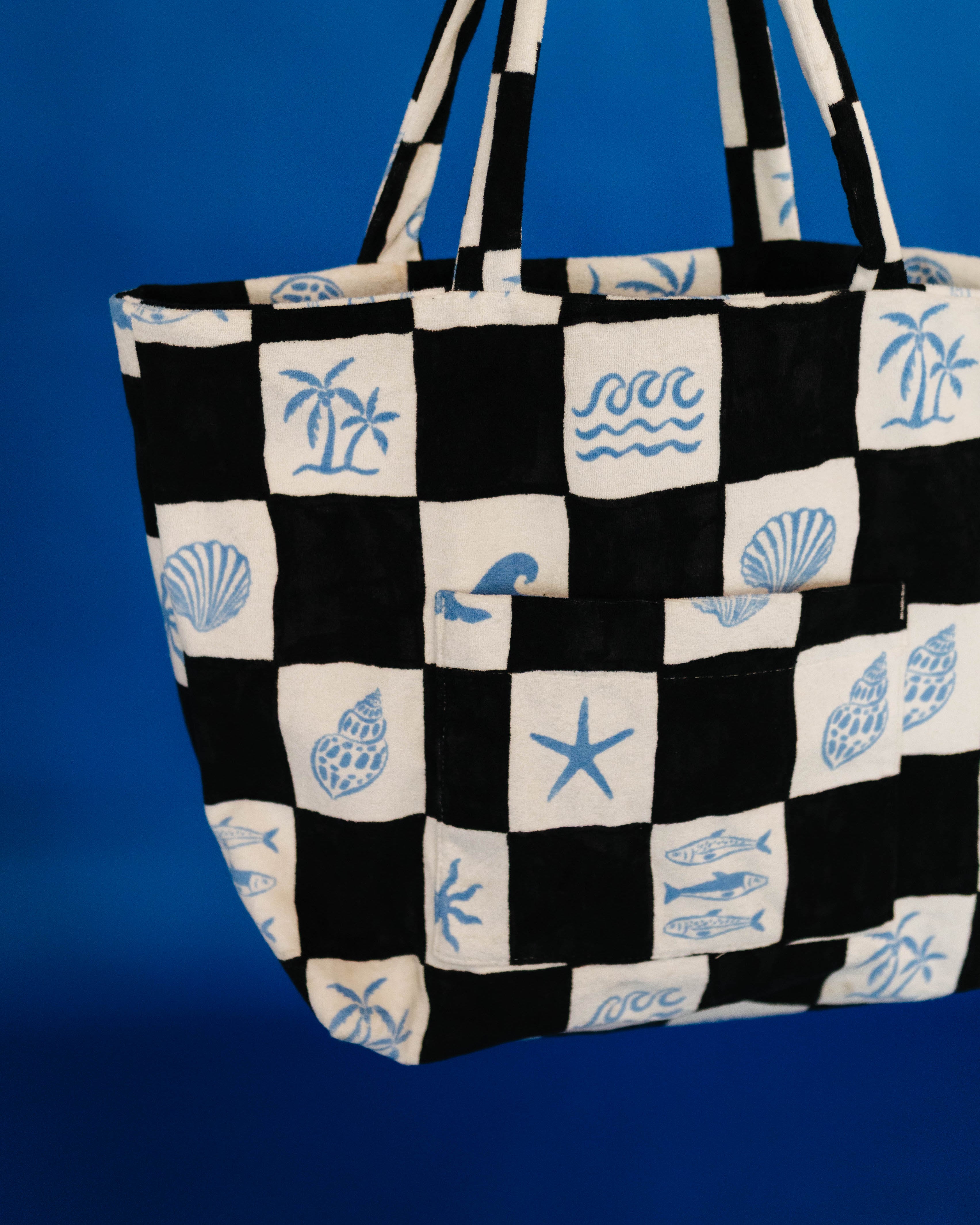 Black and white checkered tote bag with blue sea-themed patterns on a blue background