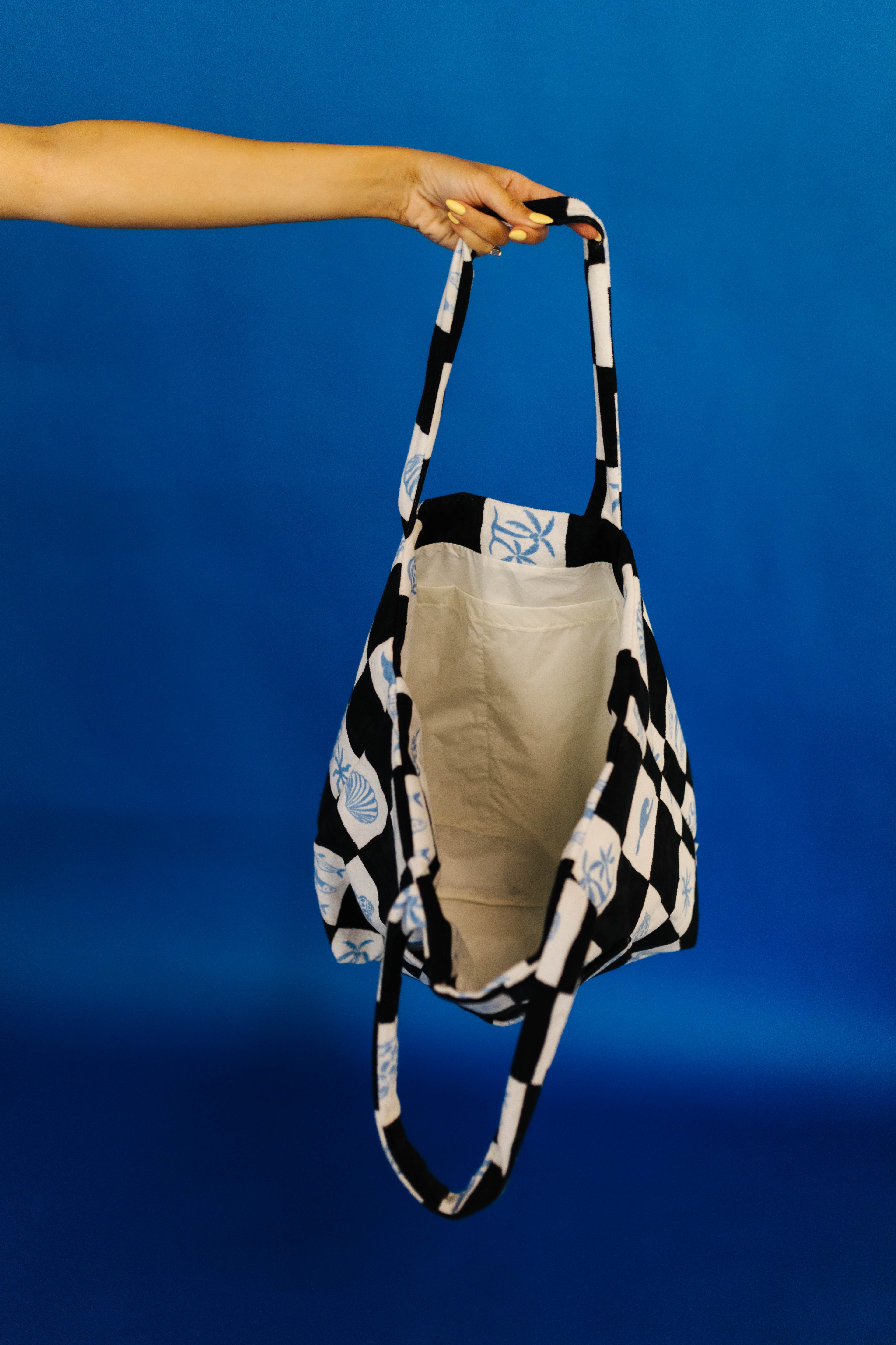 Person holding a black and white checkered bag against a blue background