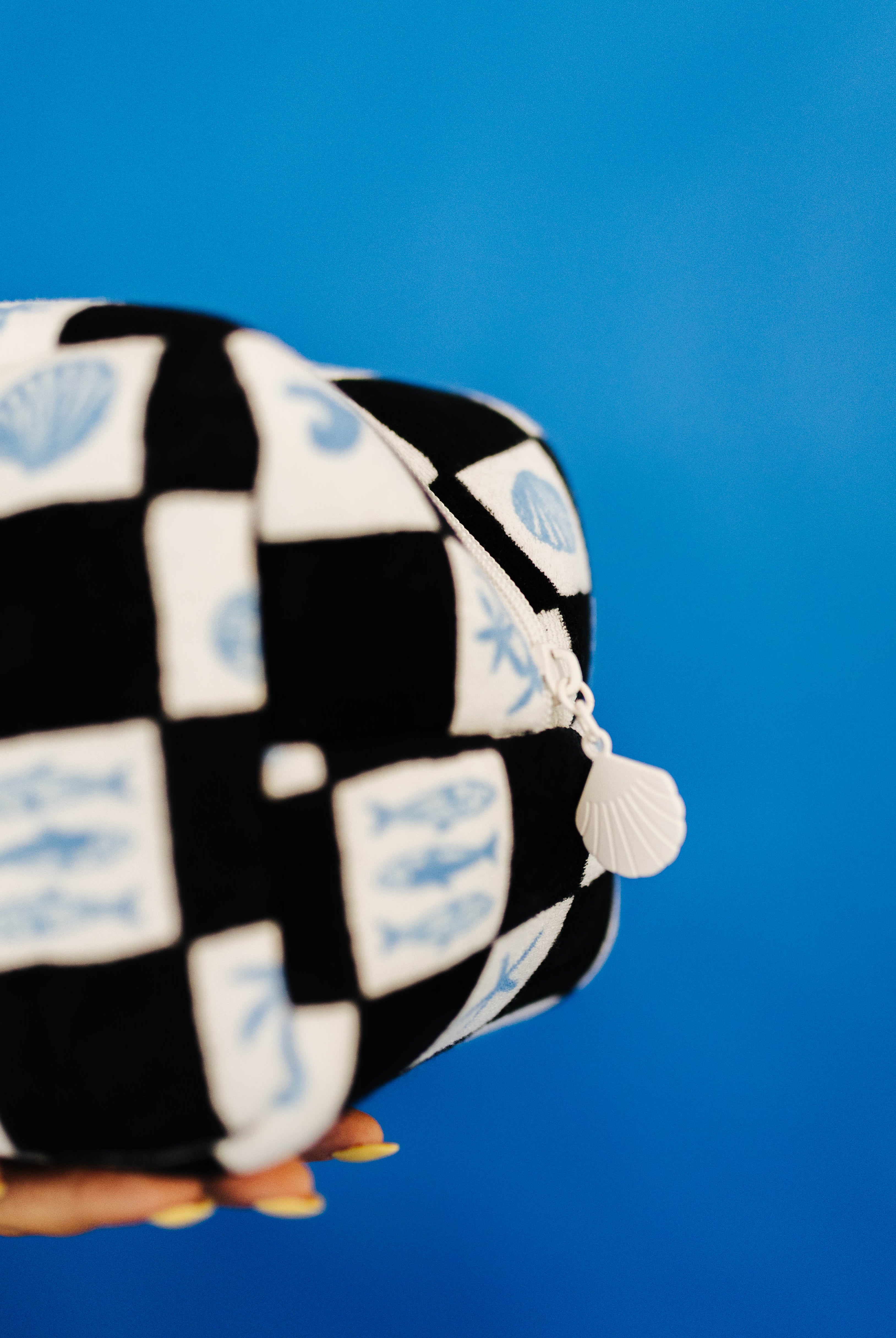 Checkered fabric item with shell charm on a blue background