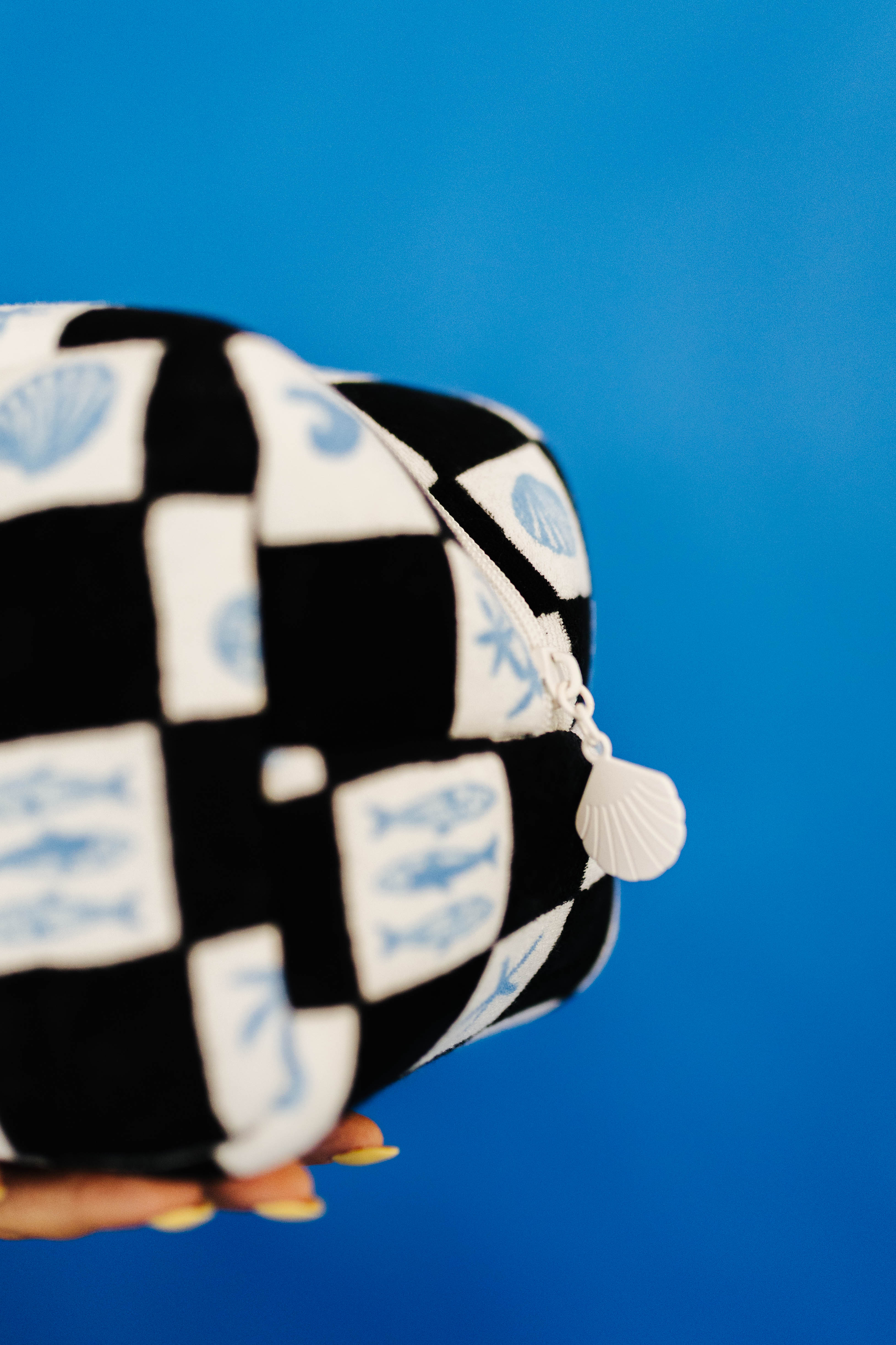 Checkered fabric item with shell charm on a blue background