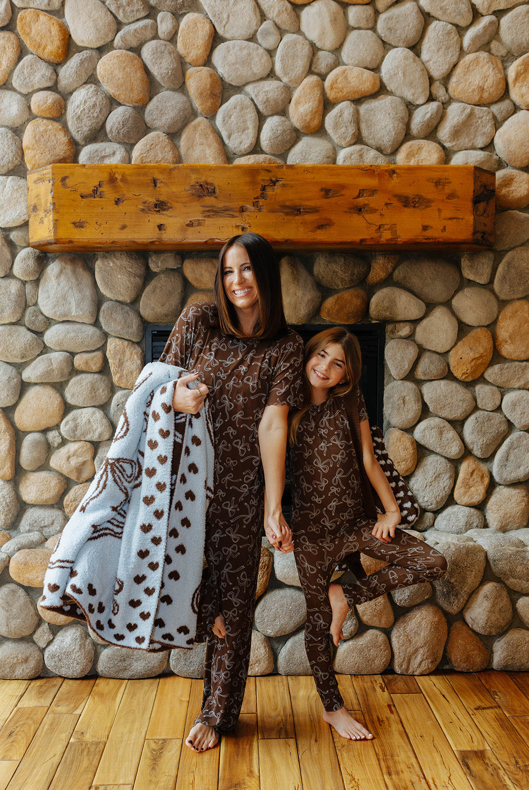 Model holding the light blue quillow with brown bow print beside a child.