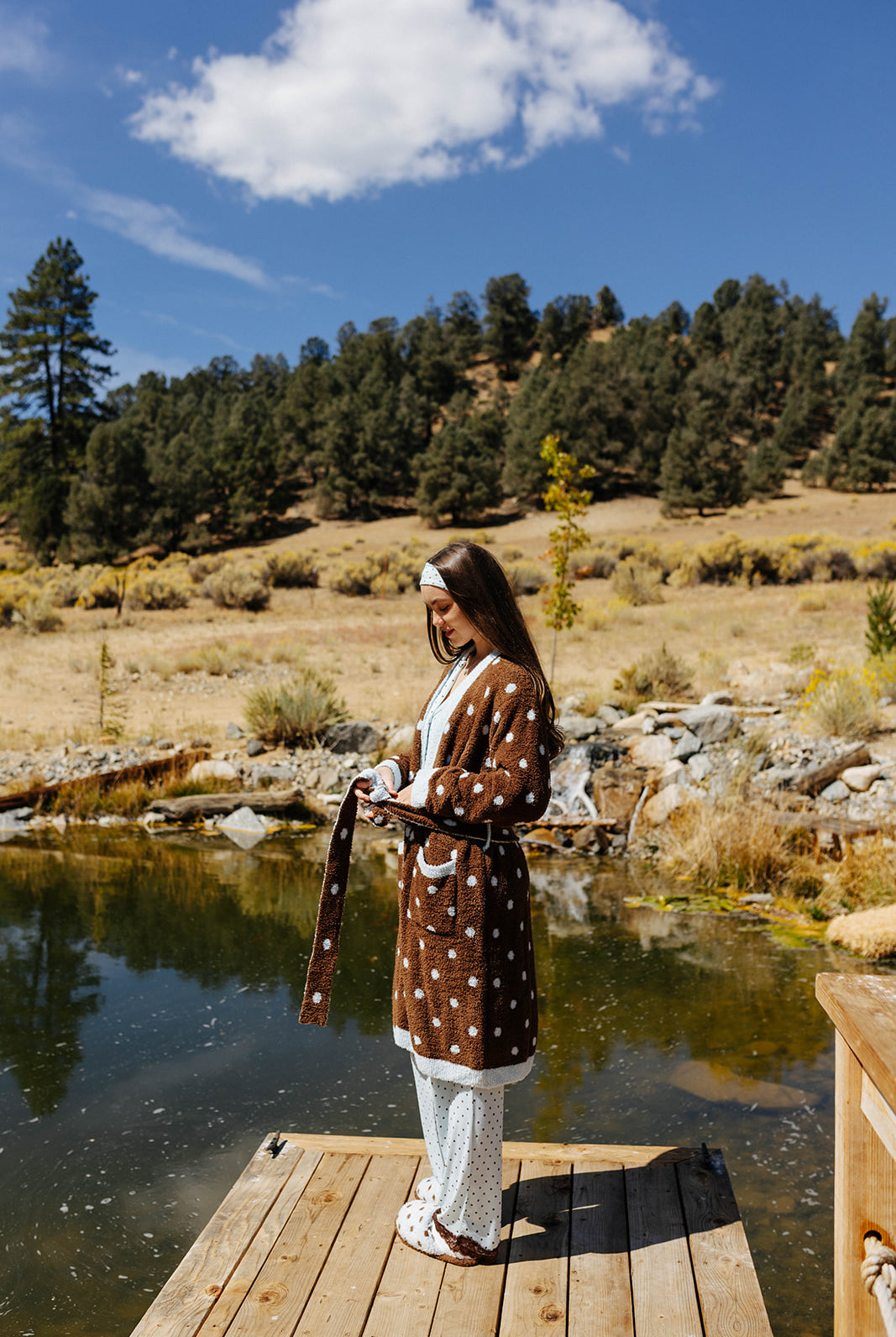 Full length front view of the brown fluffy polka dot robe tied at the waist on a dock.