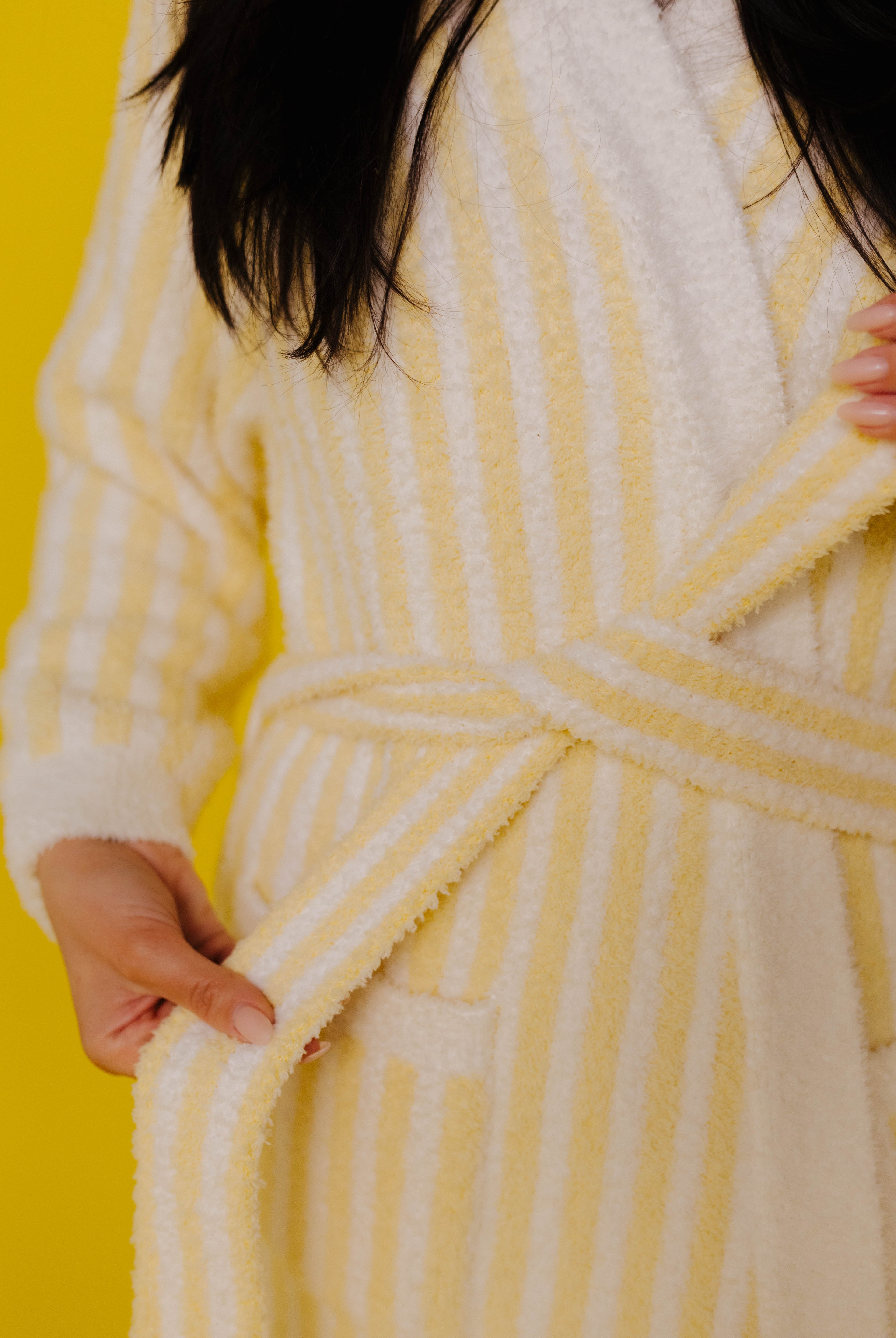 Person wearing a yellow and white striped robe against a yellow background