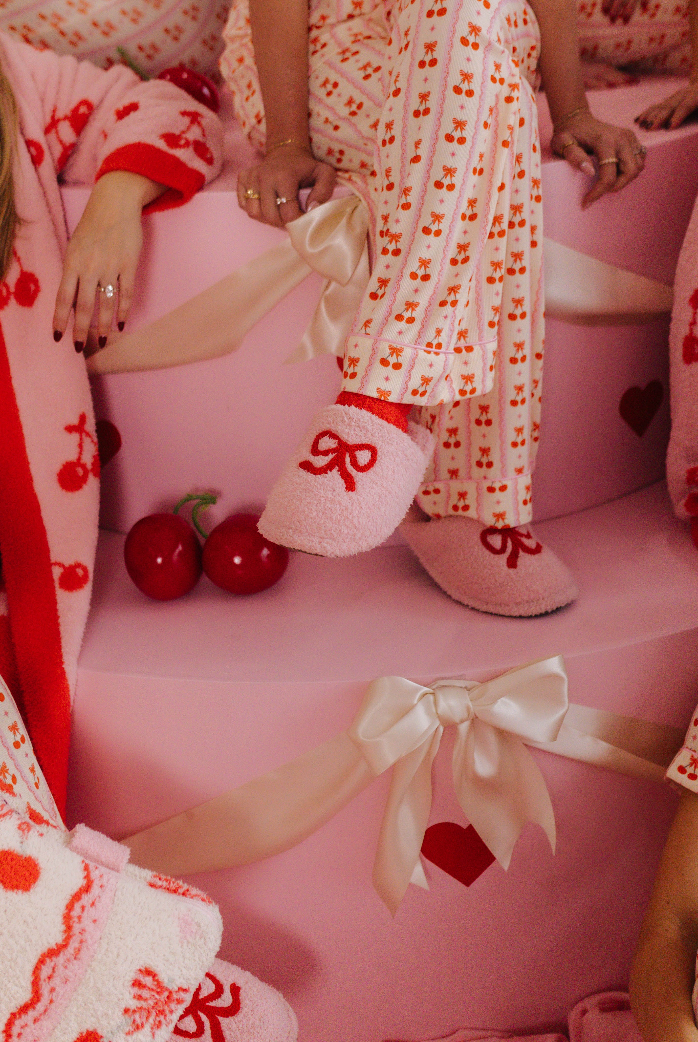 Person wearing a cherry-themed outfit with matching slippers on a pink chair.