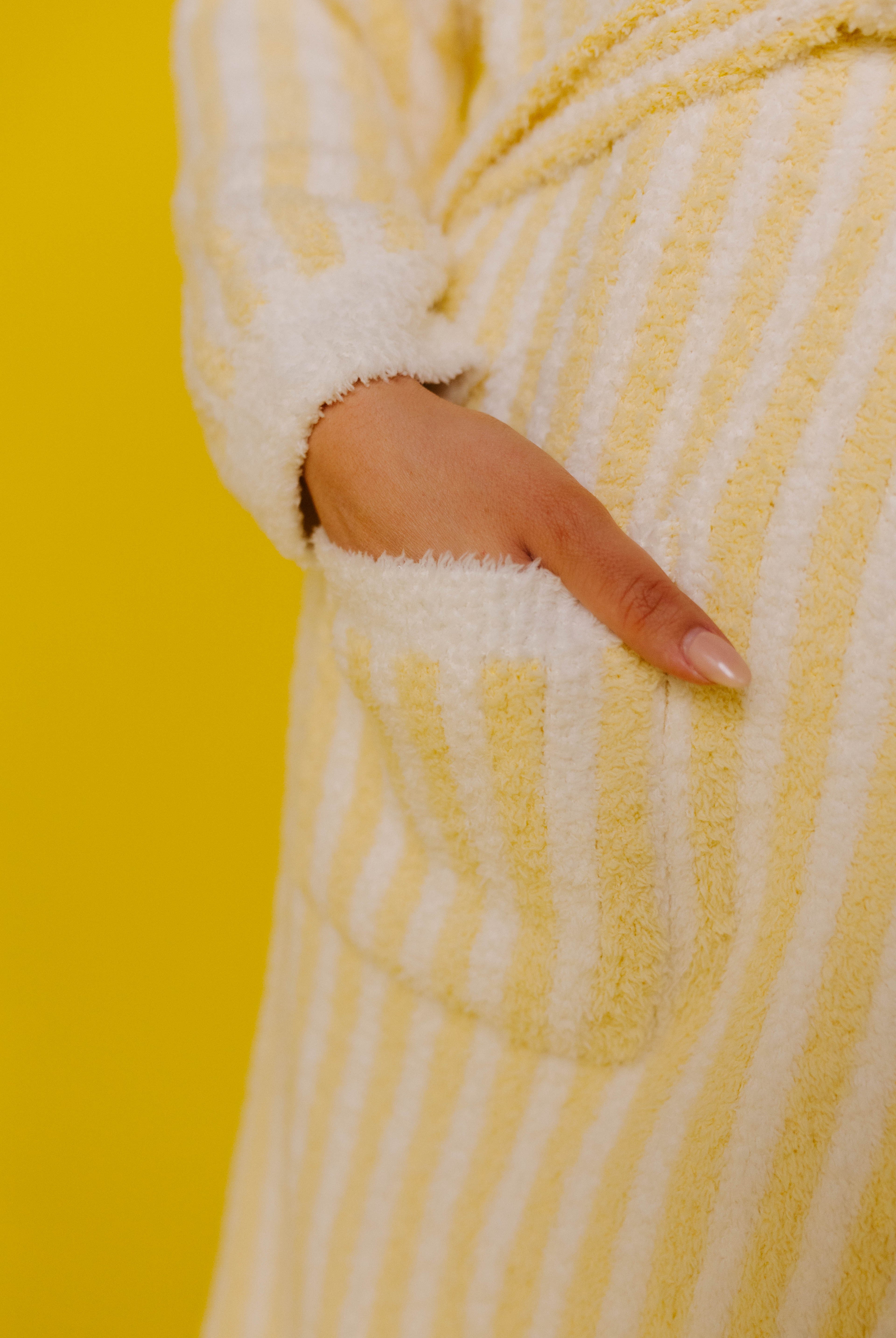 Close-up of a yellow and white striped robe with a pocket on a yellow background