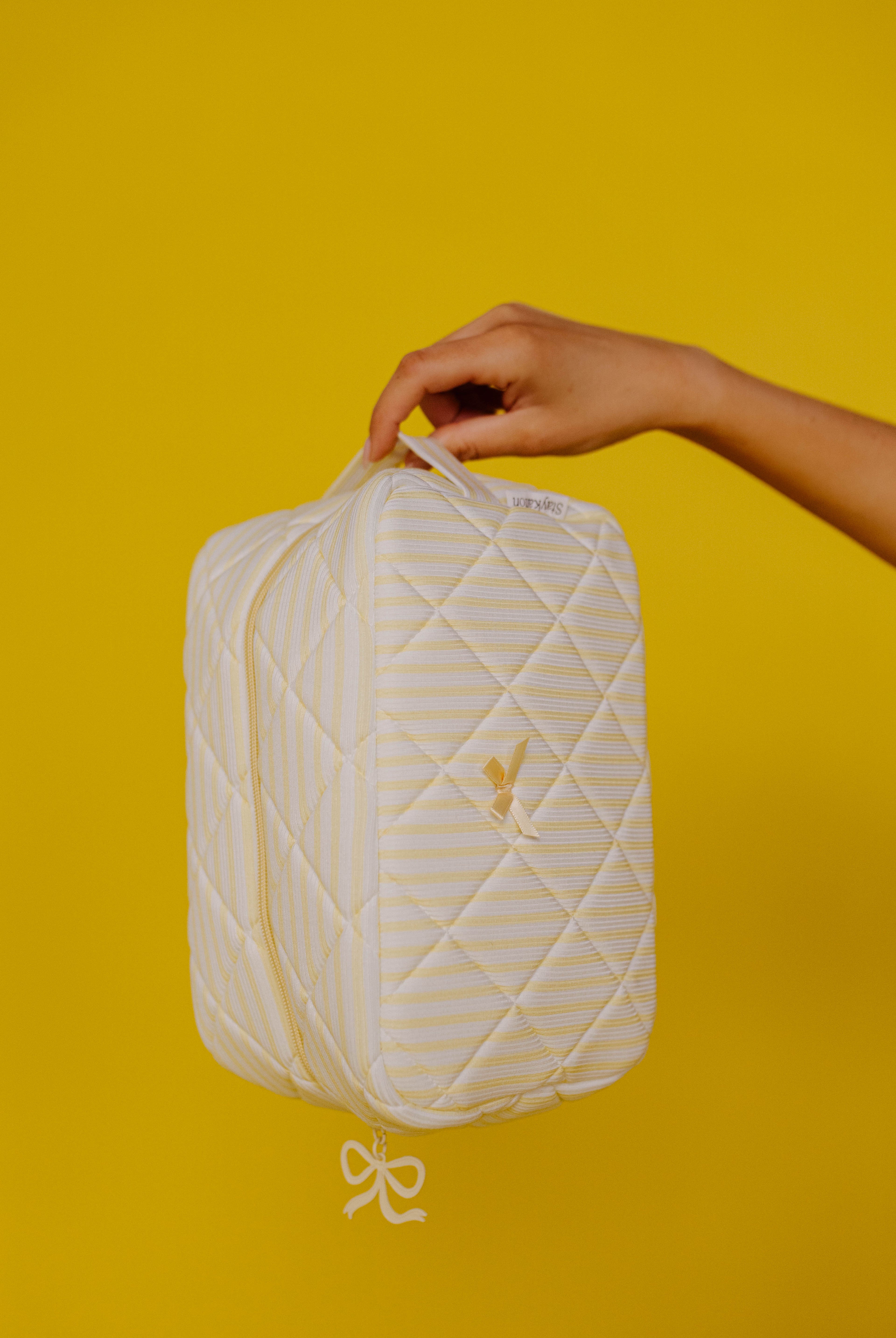 holding up the cosmetic bag on a plain yellow background