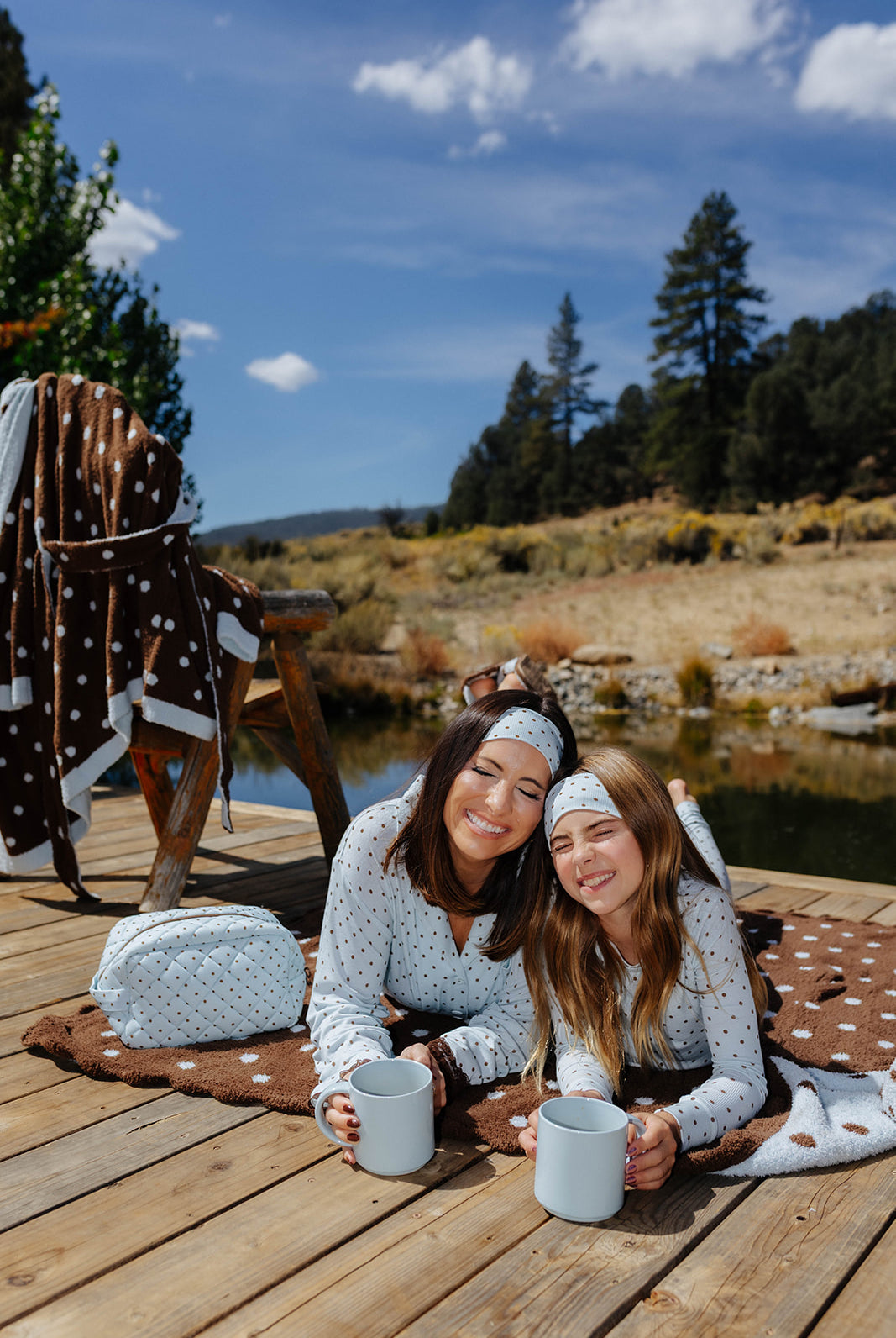 Adult and child wearing matching blue and brown polka dot pajamas, smiling on a dock.
