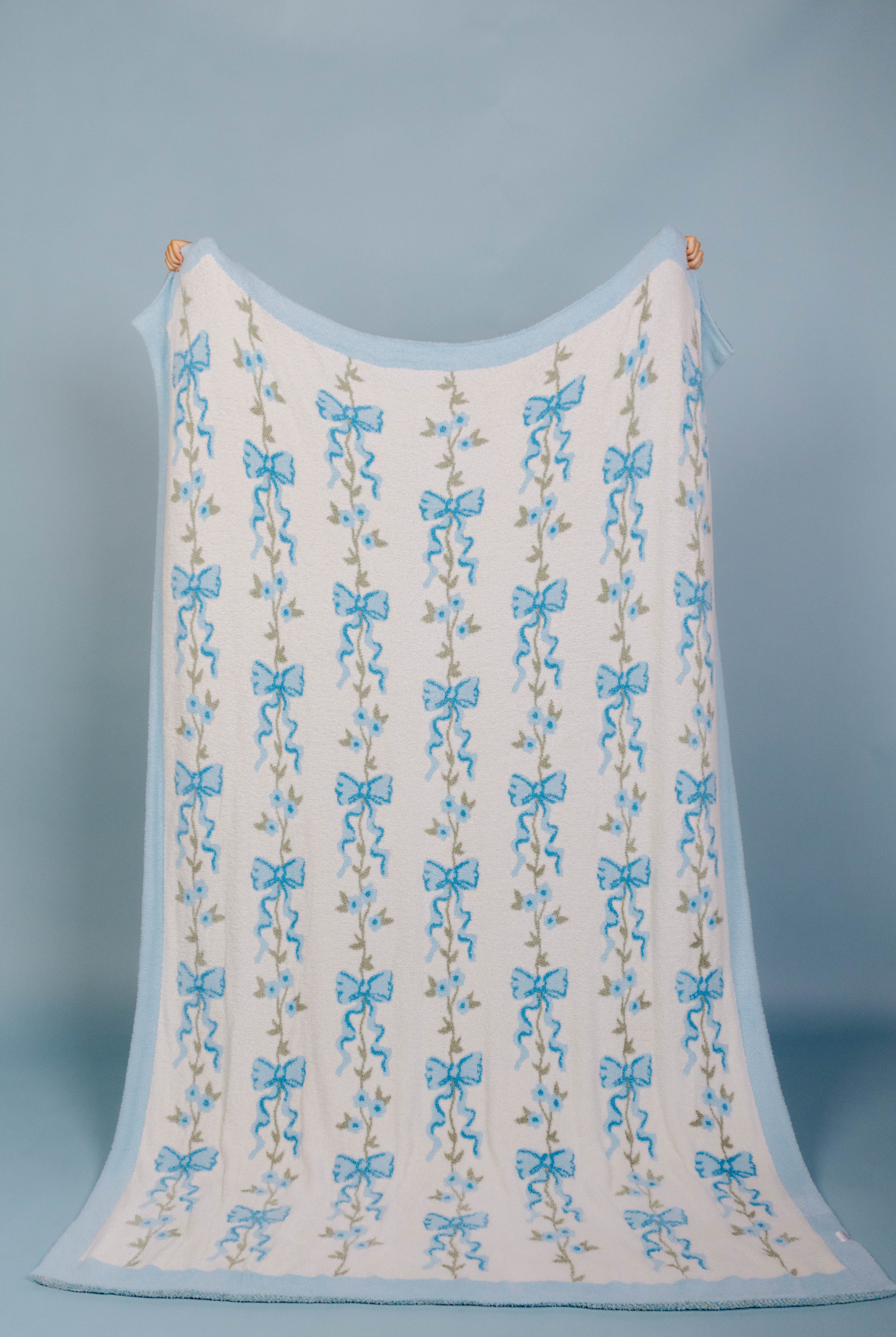 full front of the blue bow blanket being held up with a blue background