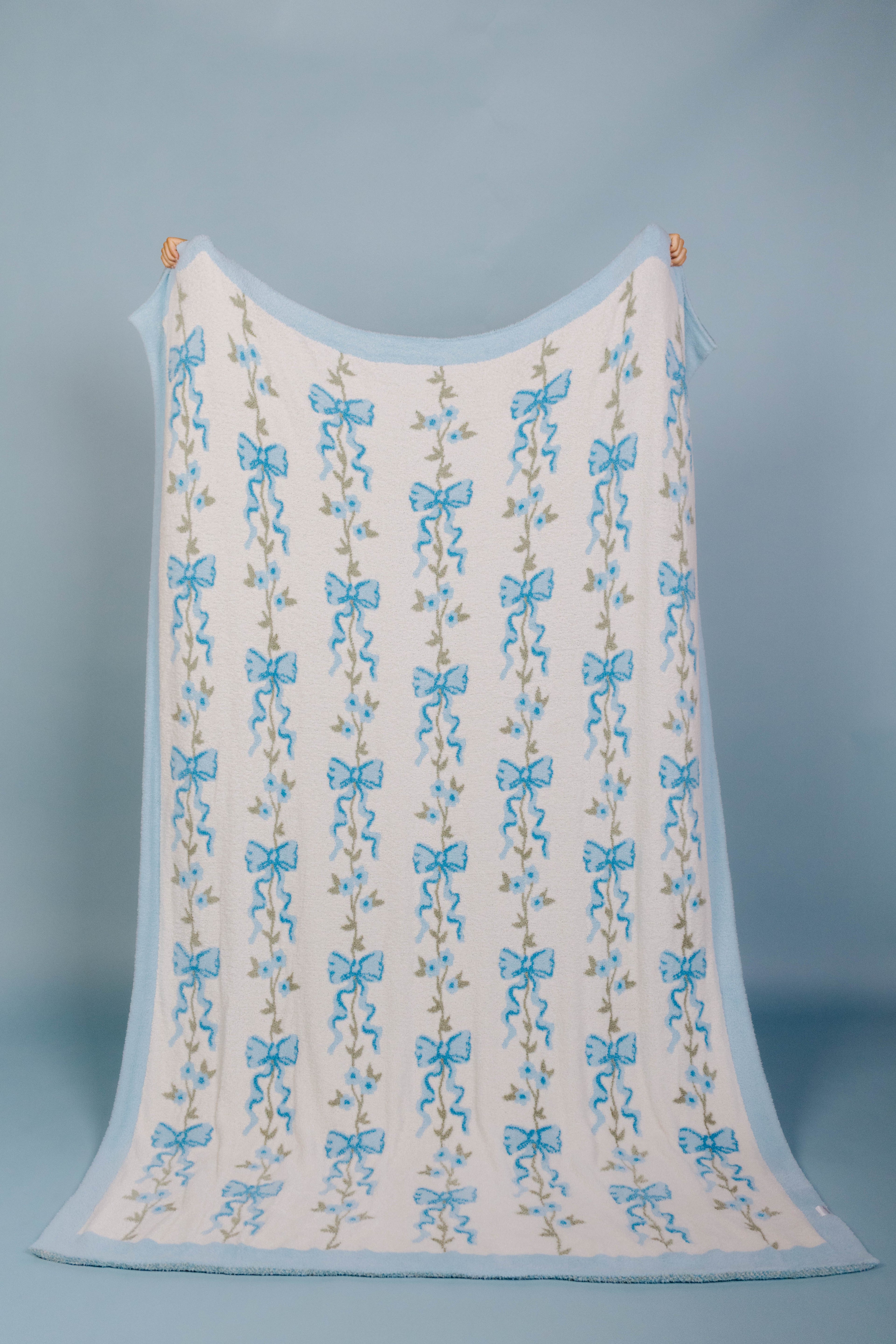 full front of the blue bow blanket being held up with a blue background