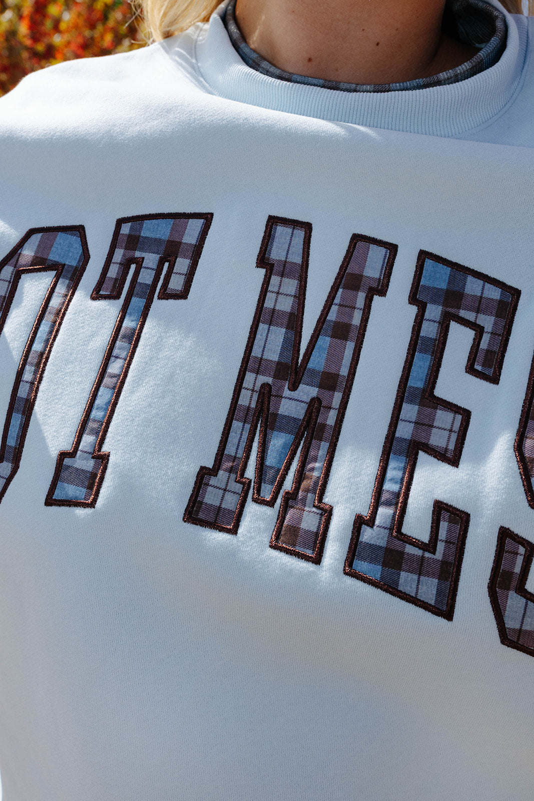 Close view of the Hot Mess sweatshirt lettering in brown plaid.