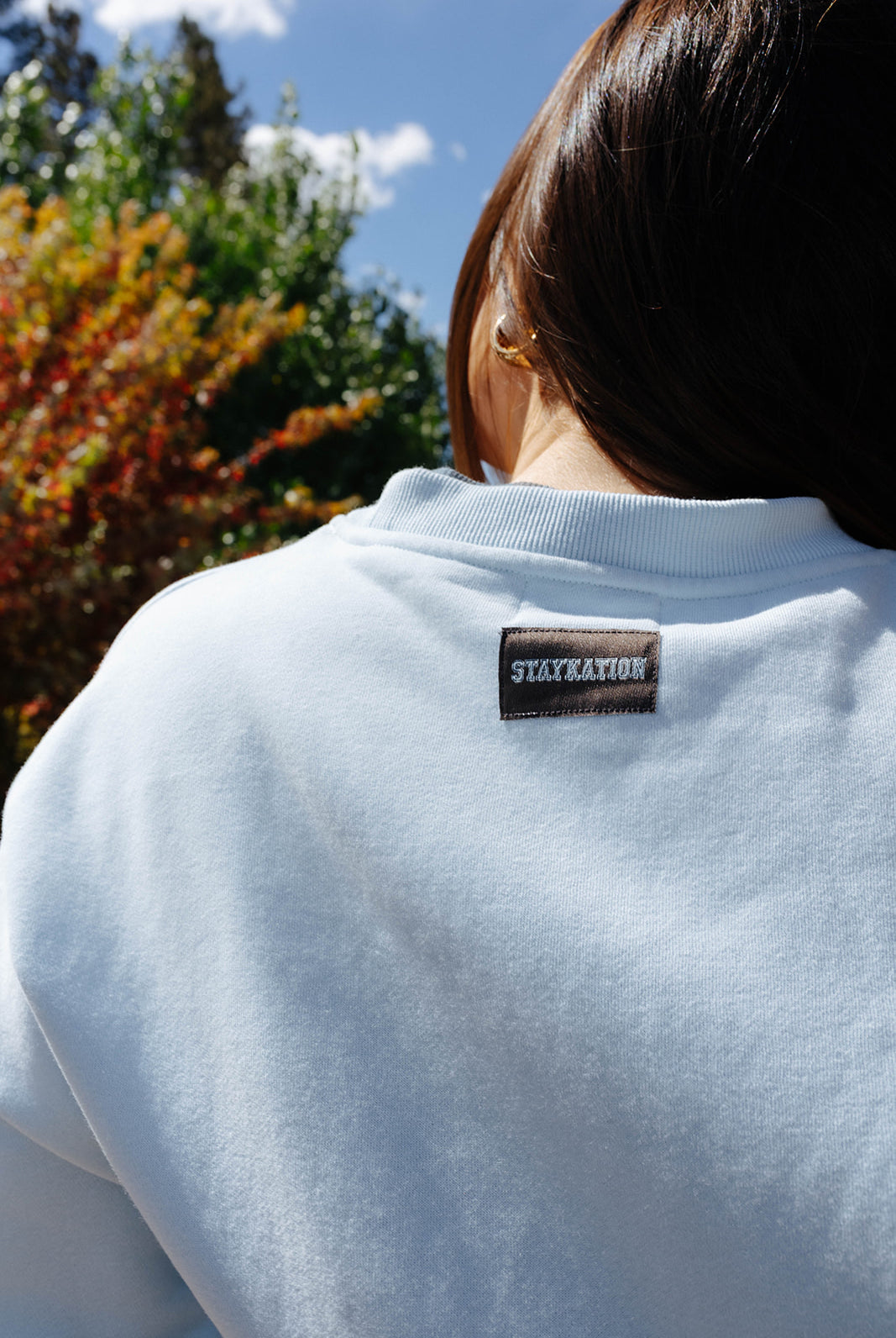 Back neckline and Staykation label on the light blue sweatshirt.