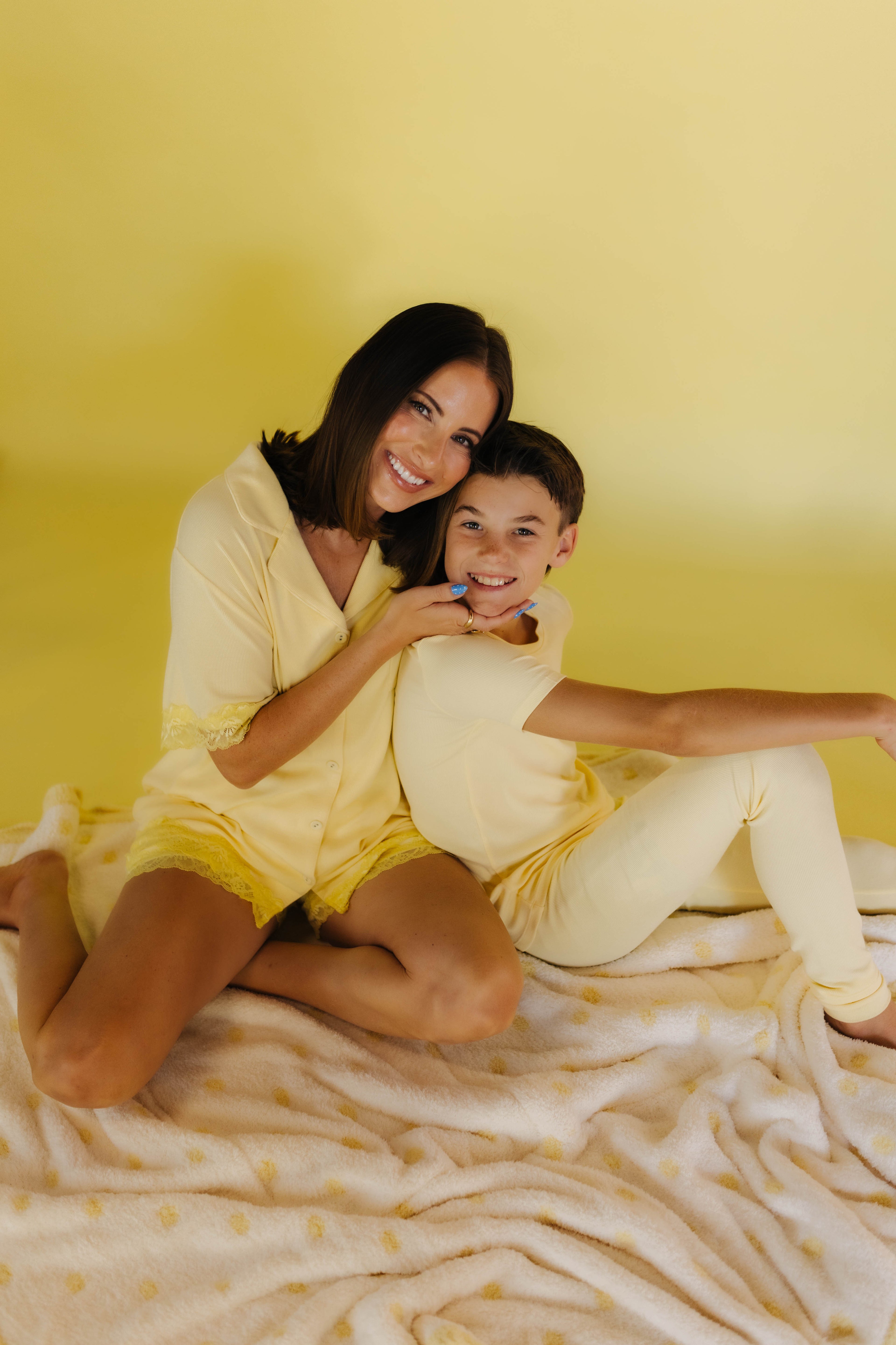 Boss and Krista smiling on the white and yellow polka quillow