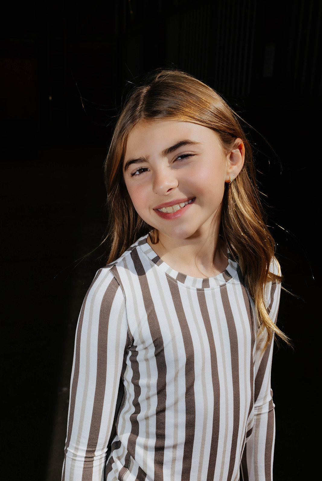 Close view of a child in the brown and cream striped pajama top.