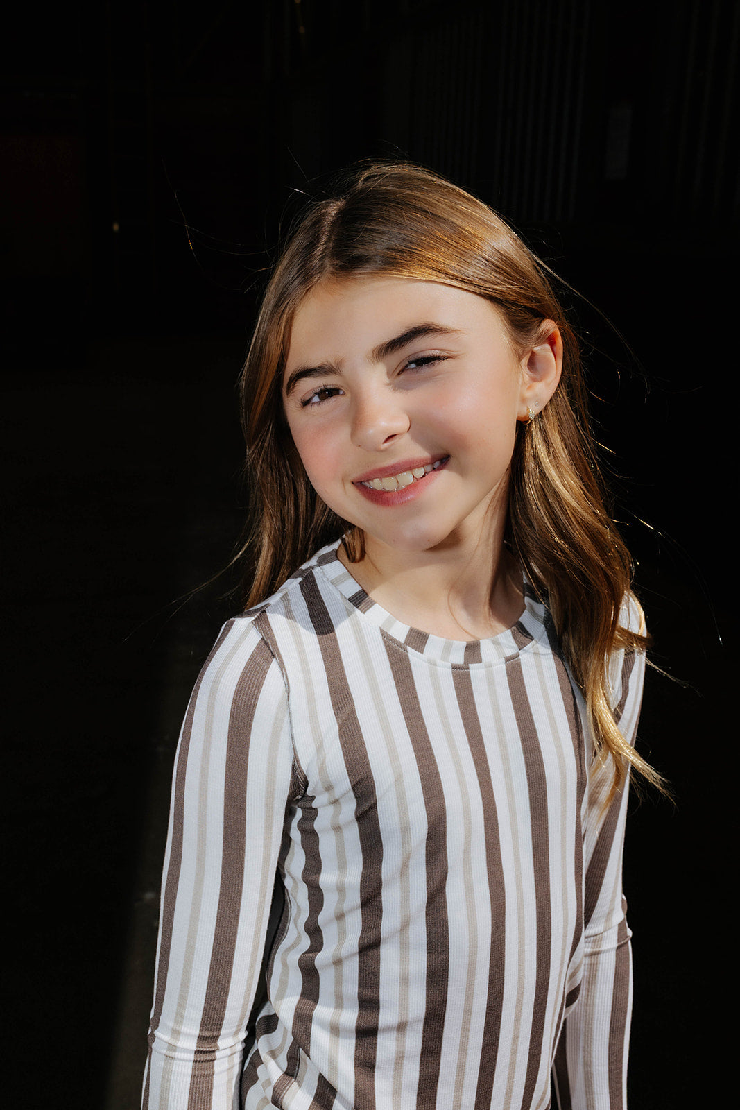 Close view of a child in the brown and cream striped pajama top.