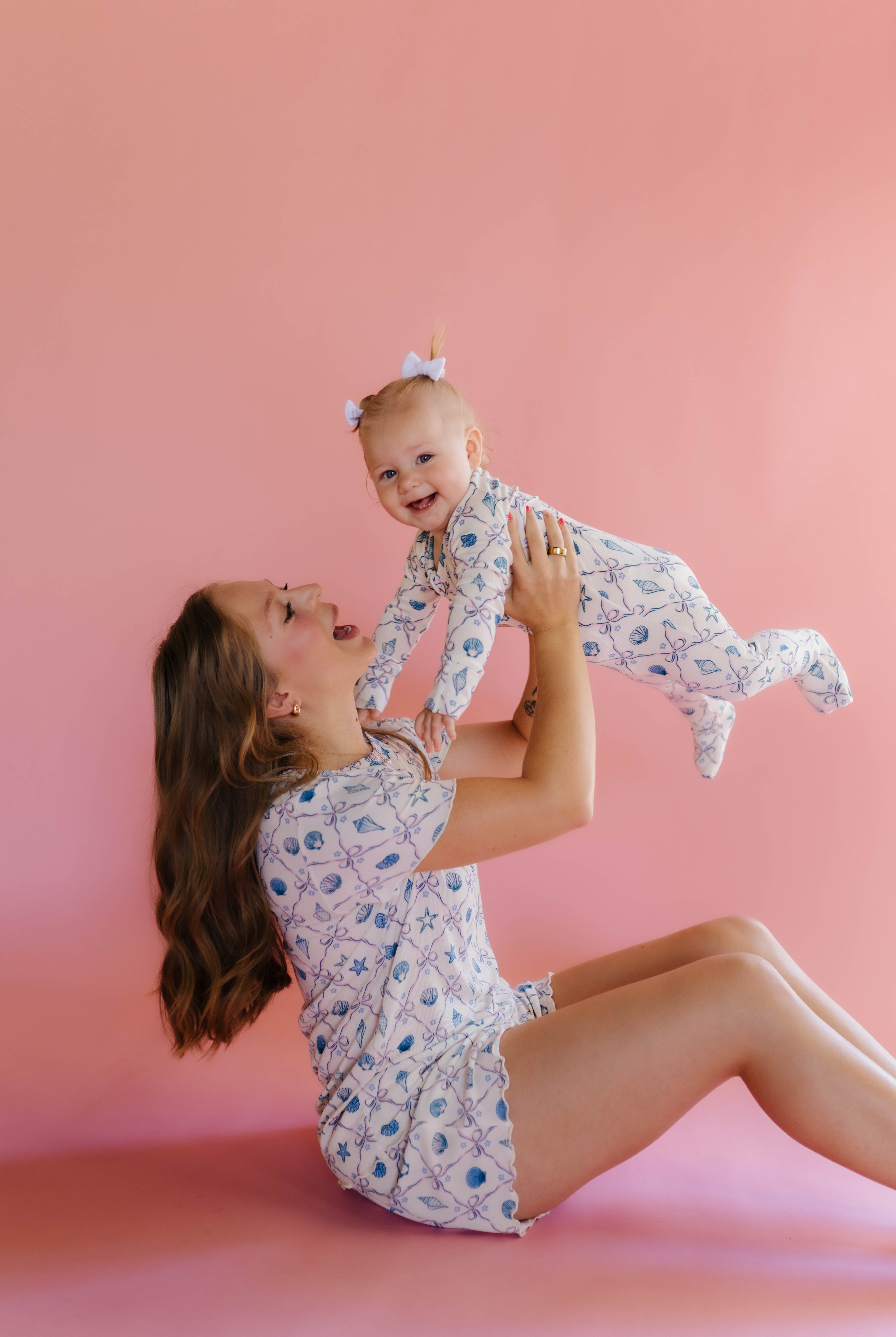 Woman and baby in matching pjs against a pink background