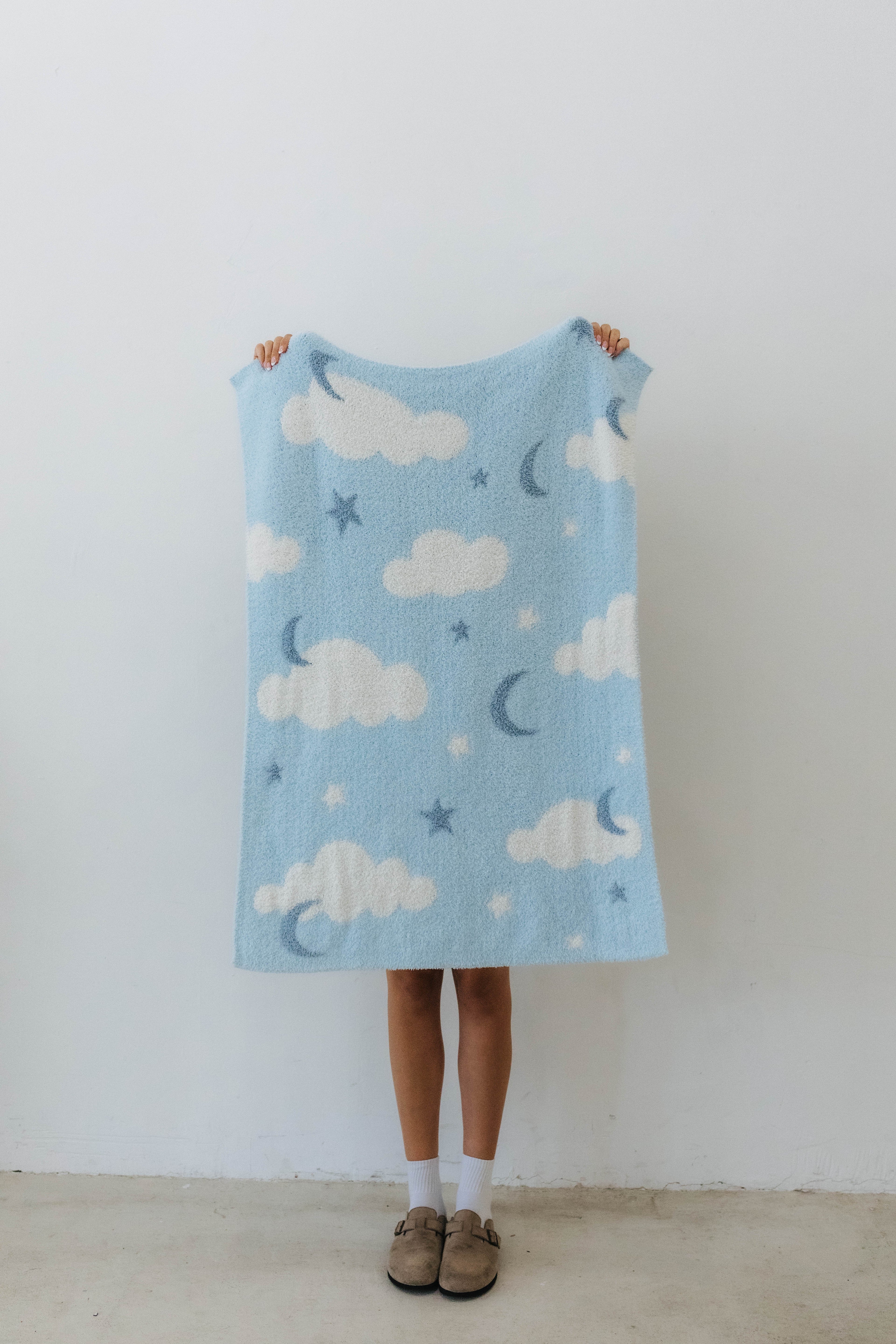 one side of the cloud baby blanket showing moon, clouds, and stars print