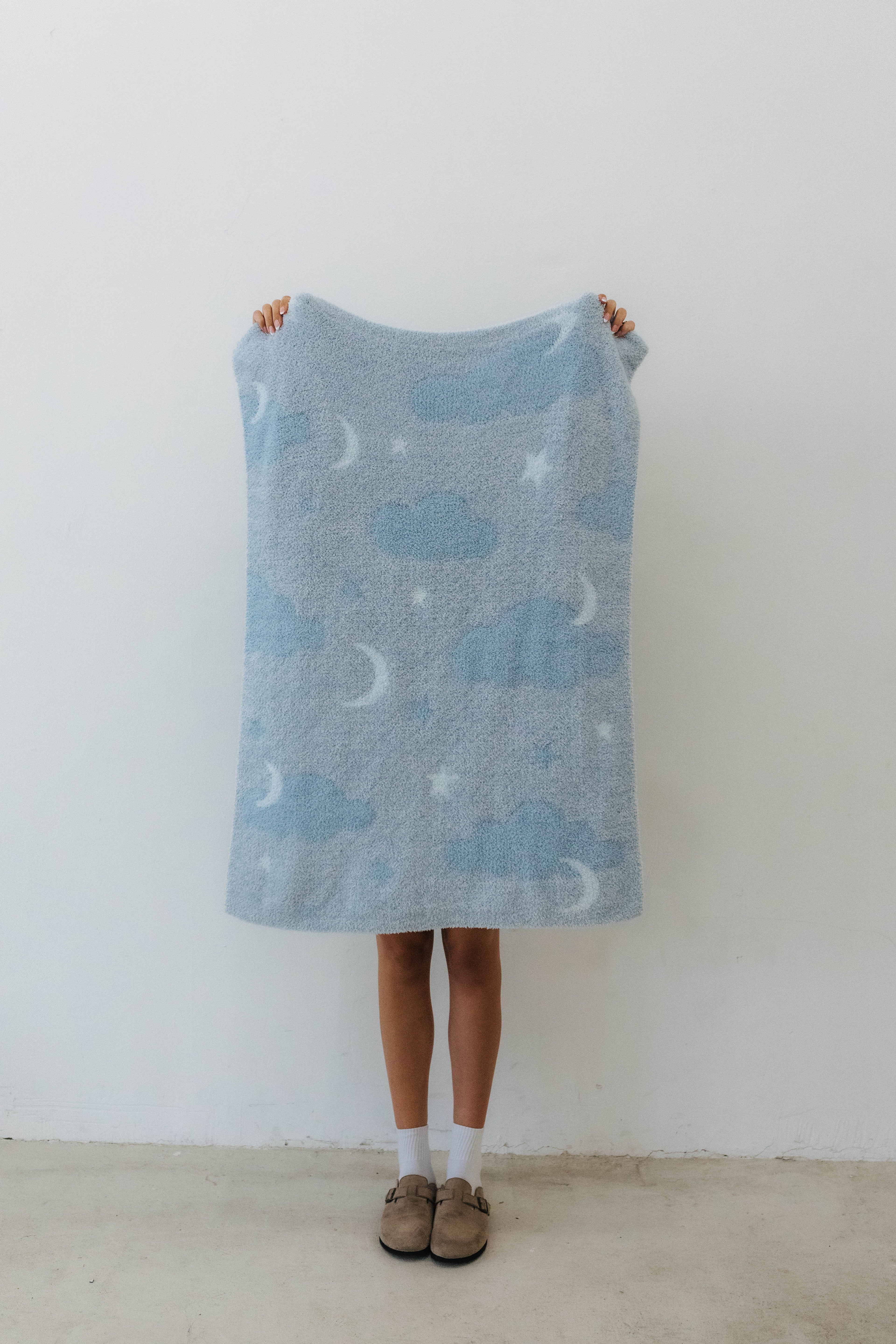 one side of the cloud baby blanket showing moon, clouds, and stars print
