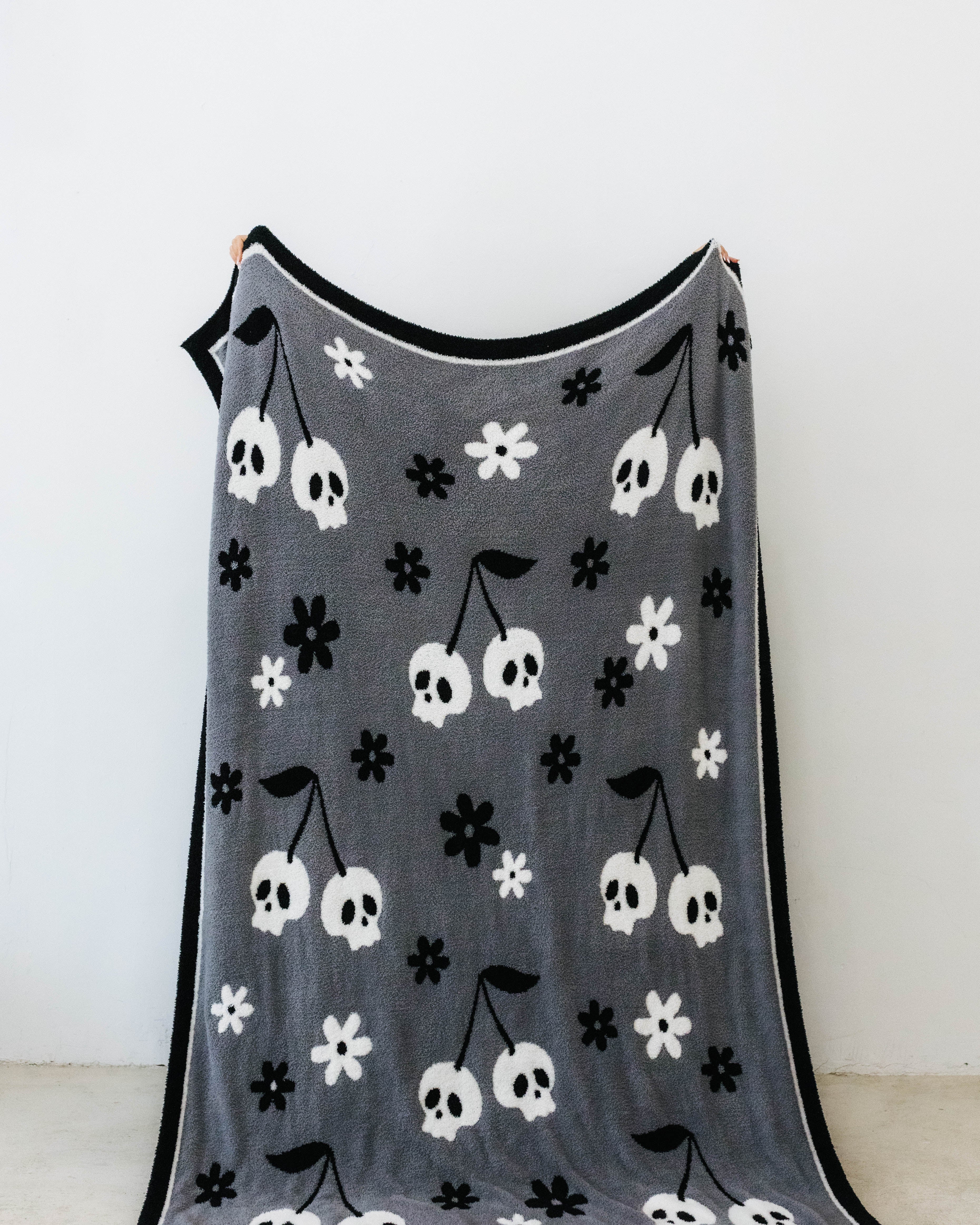 one side of skelly blanket showing skelly cherry print and flowers