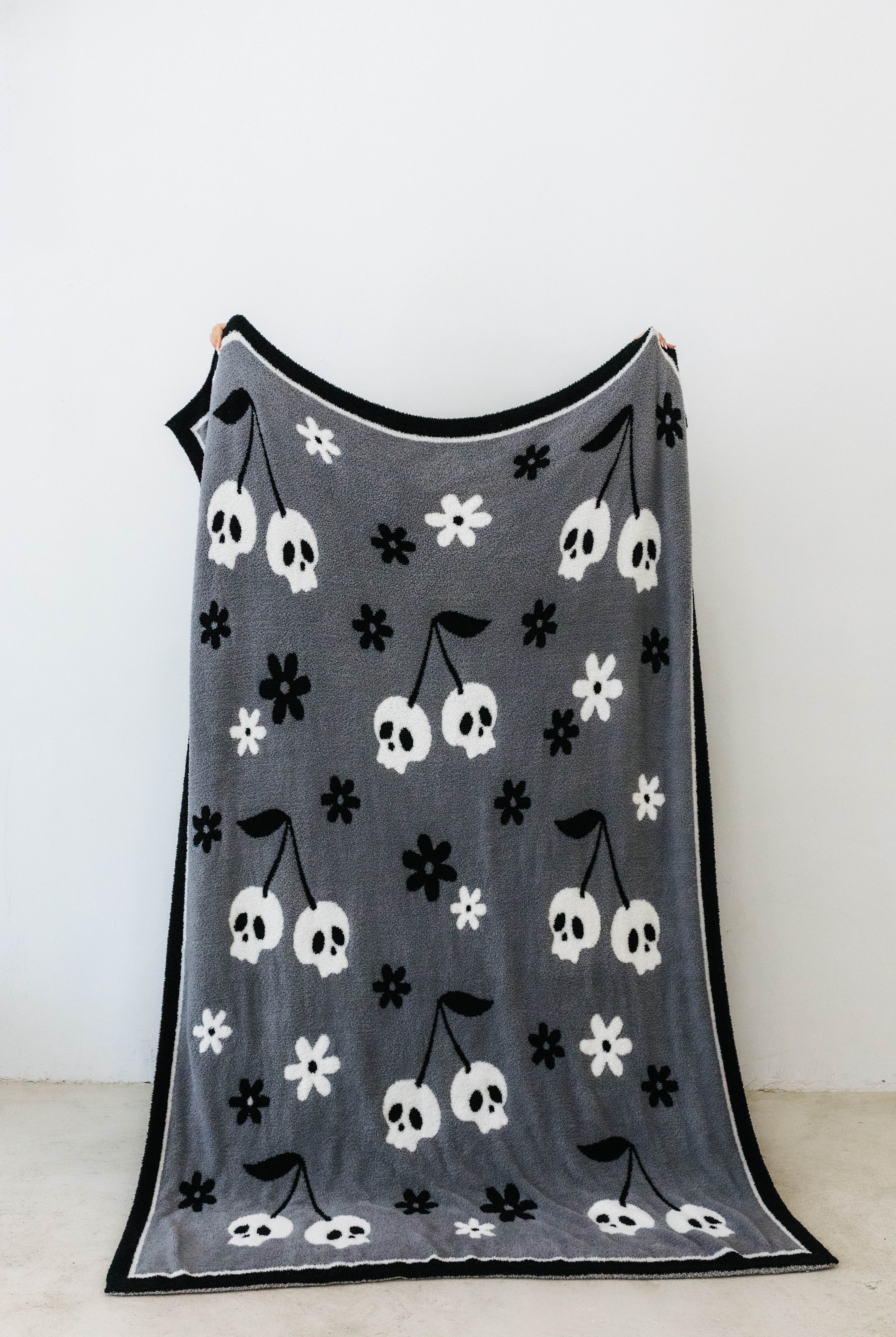 one side of skelly blanket showing skelly cherry print and flowers