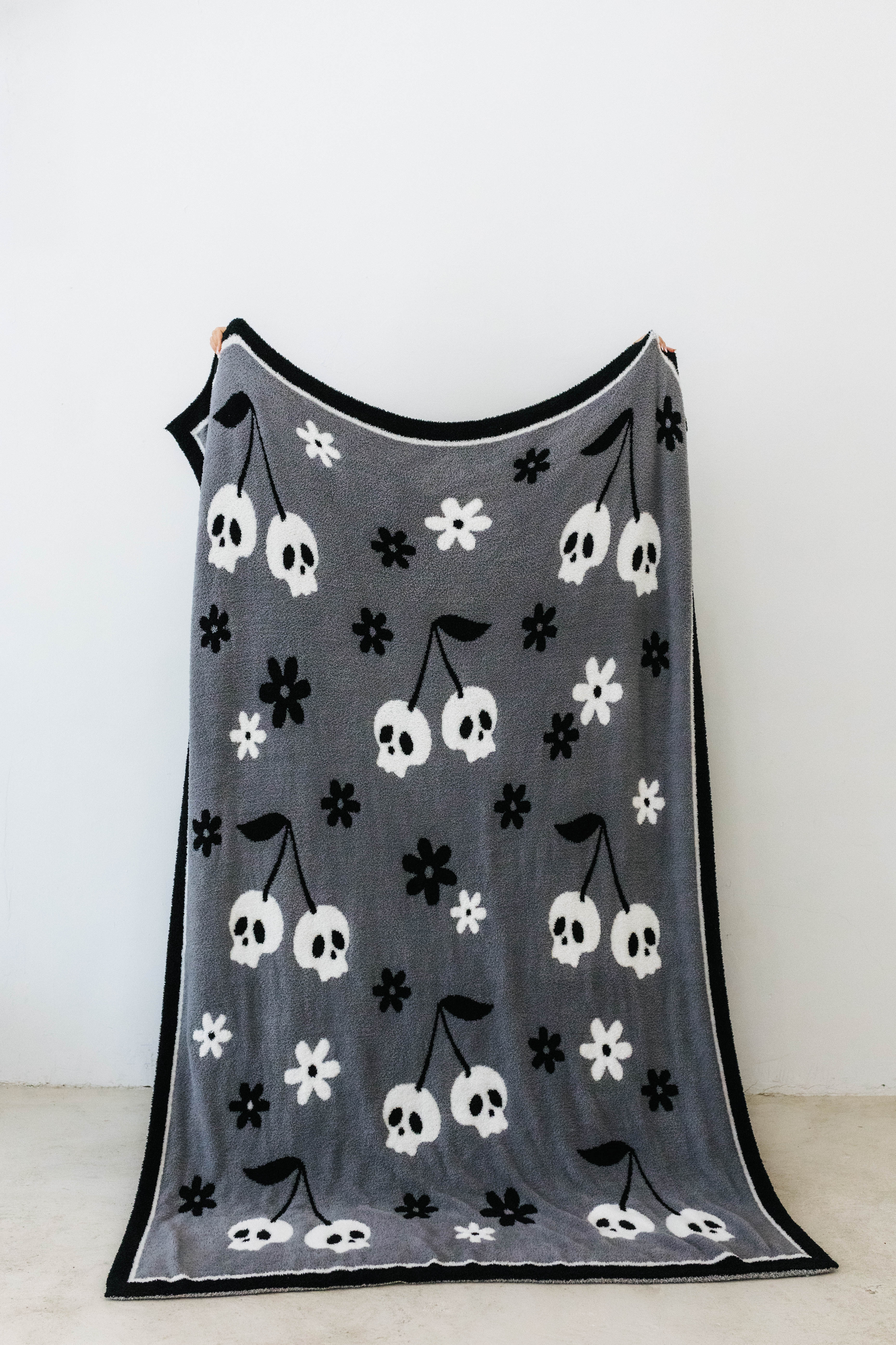 one side of skelly blanket showing skelly cherry print and flowers