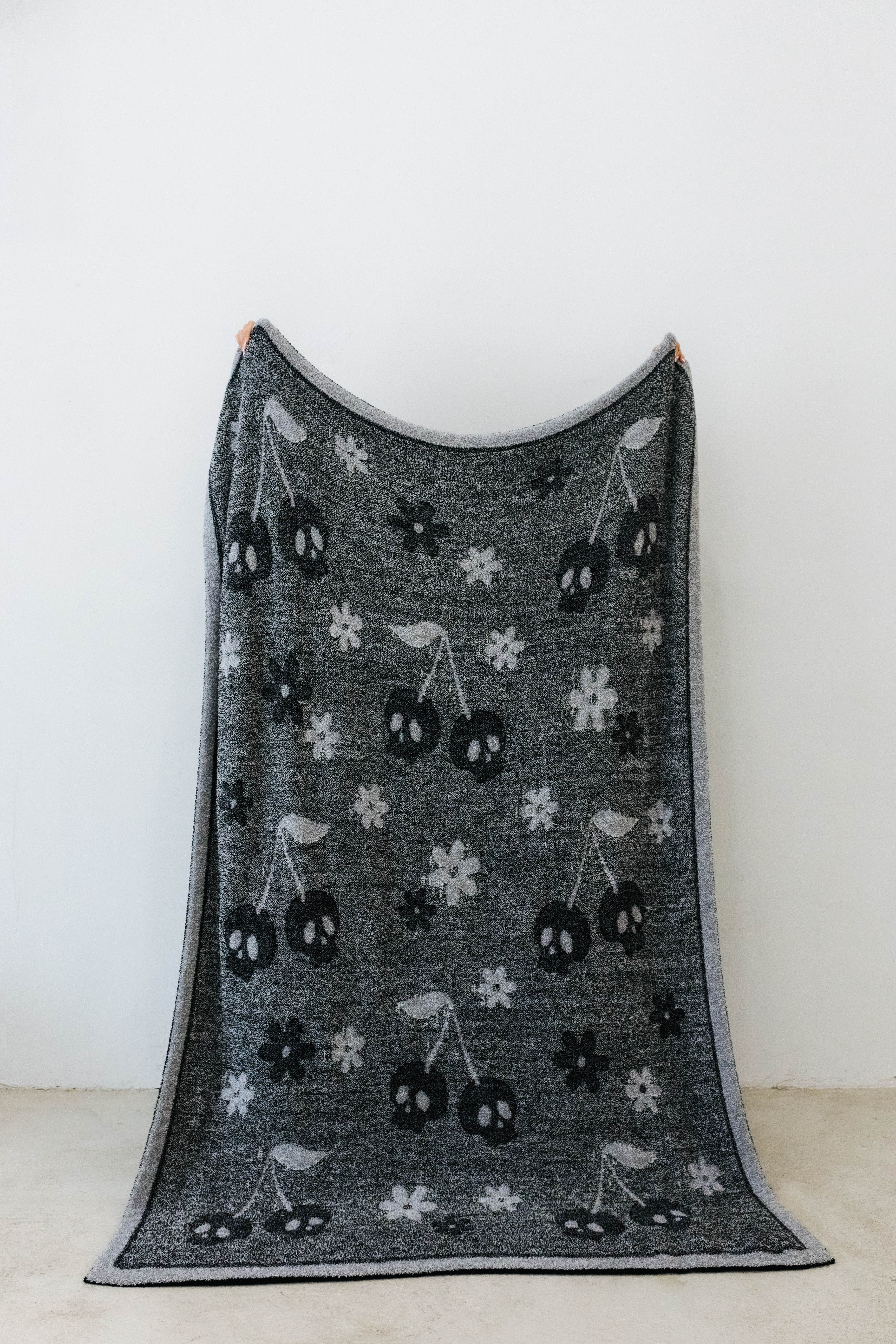 one side of skelly blanket showing skelly cherry print and flowers