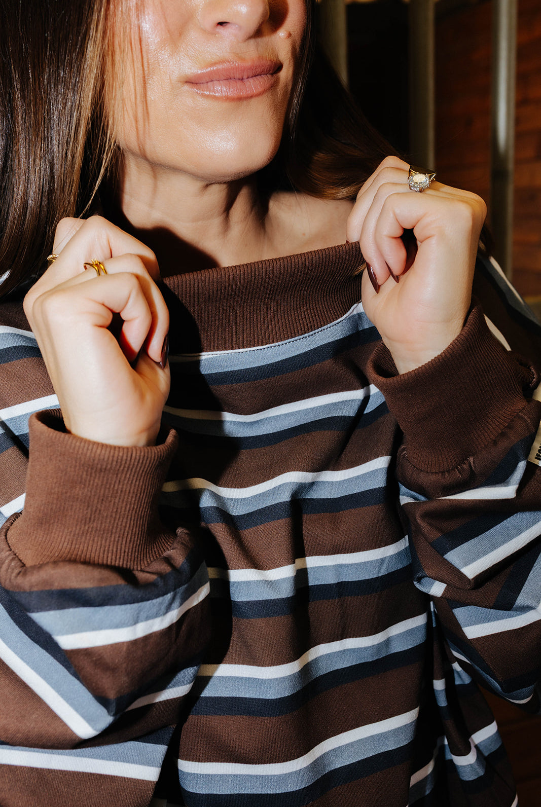 Close view of the brown ribbed neckline on the striped sweatshirt.