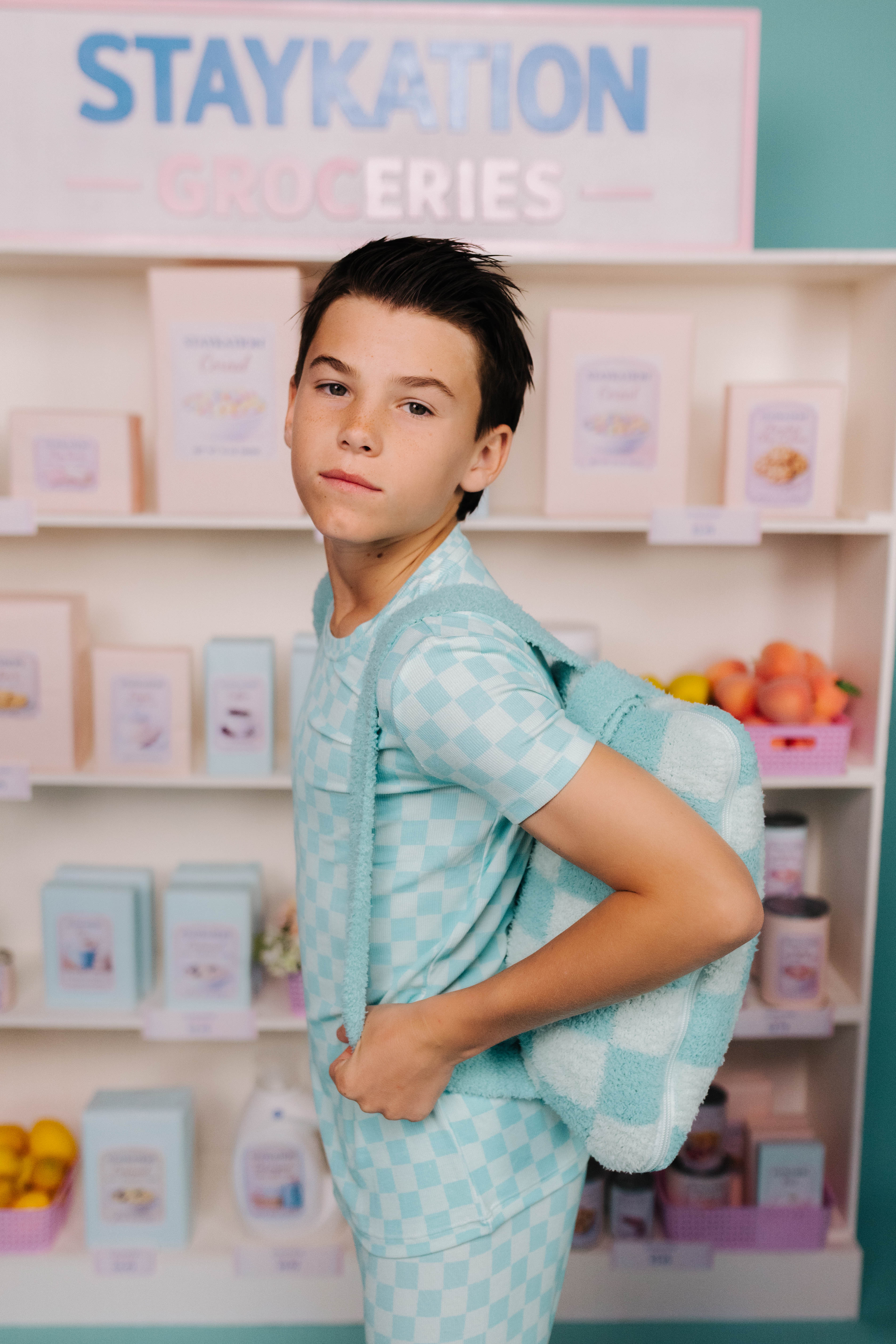 Young boy in a light blue checkered outfit with a quillow on his back
