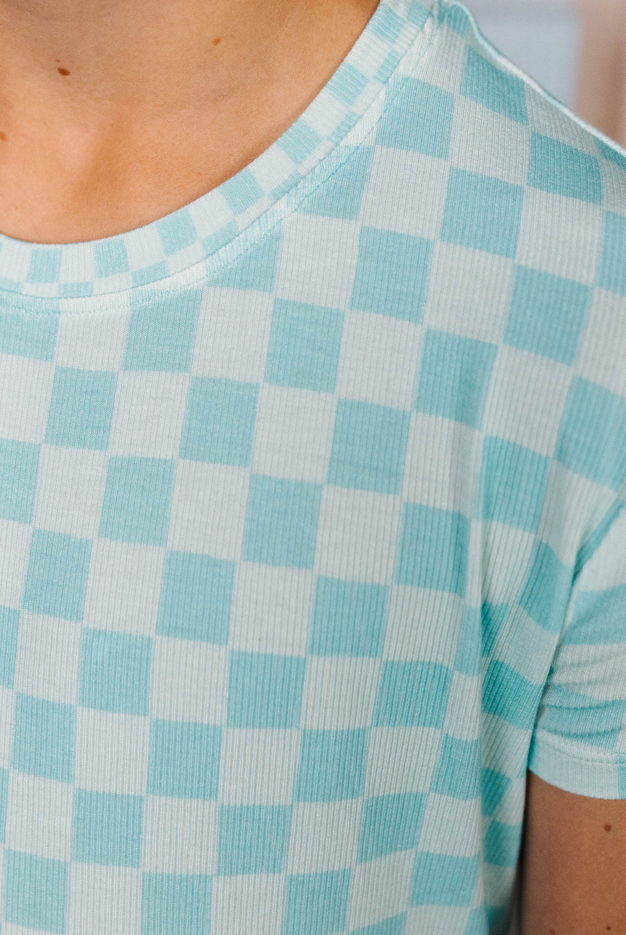 Close-up of a person wearing a teal check pj - top piece