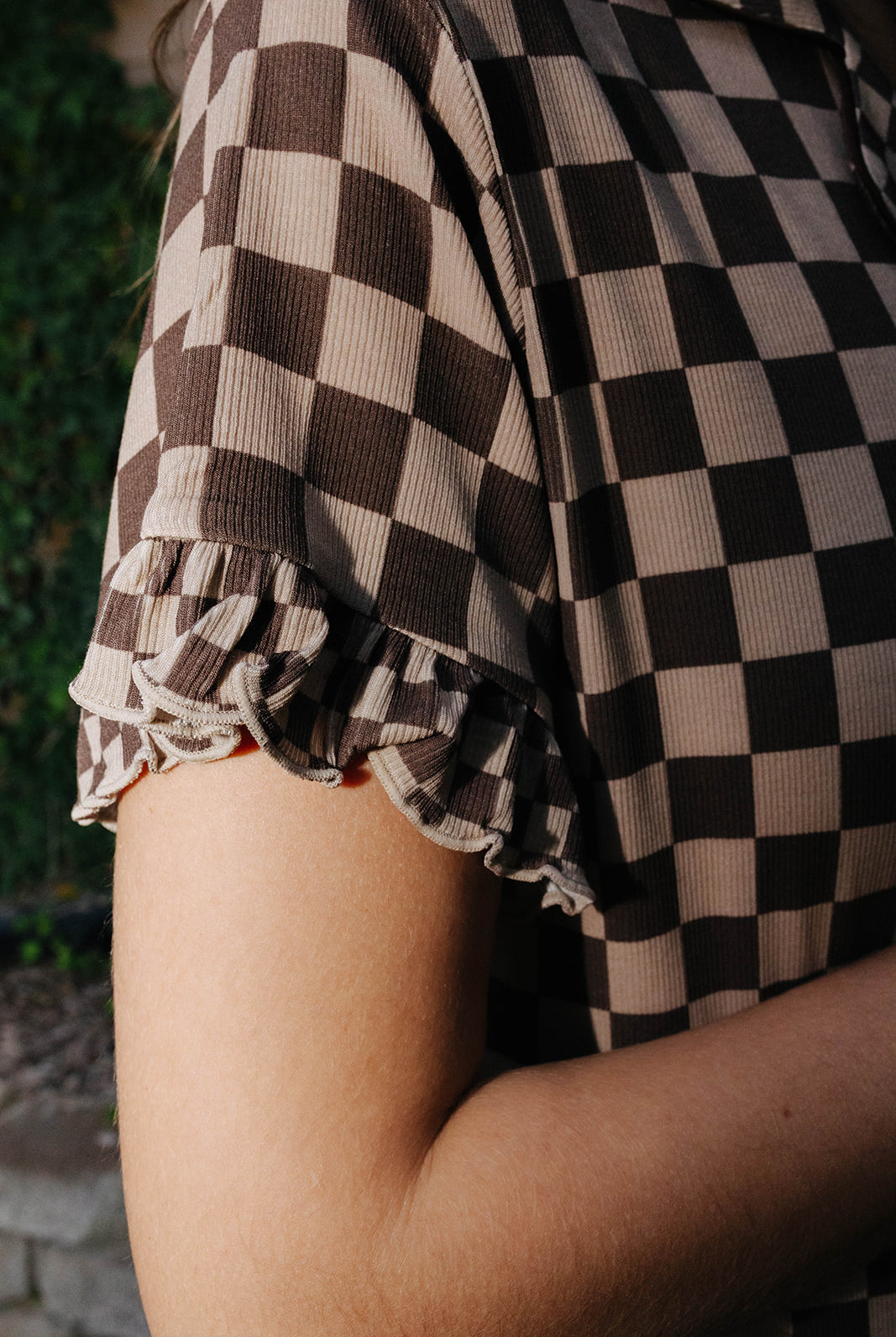 Close view of the brown check pajama shirt sleeve and scalloped edge.