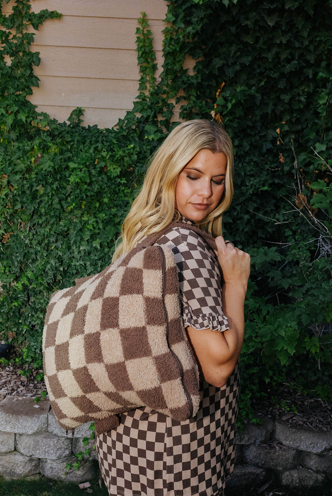 Model carrying the brown check quillow as a backpack.