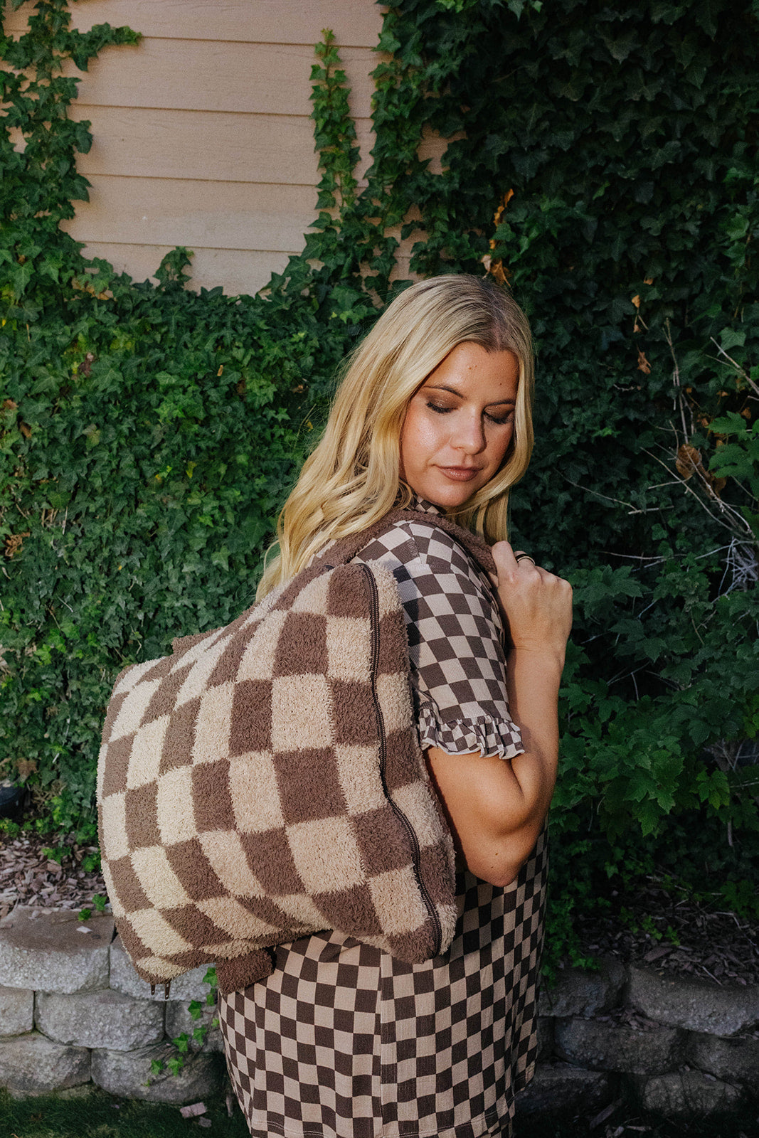 Model carrying the brown check quillow as a backpack.