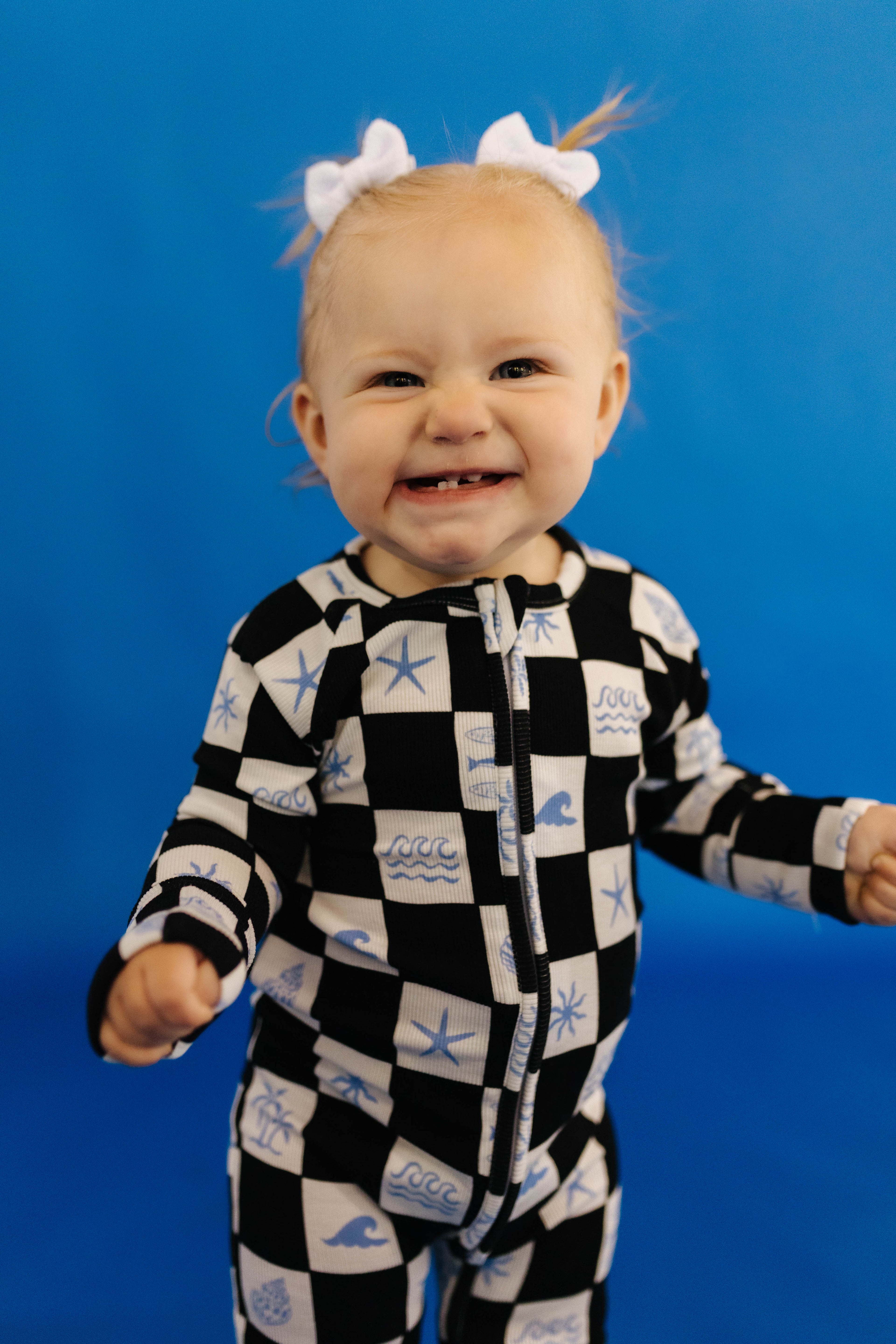 Child wearing a black and white checkered onesie with blue sea-themed designs against a blue background